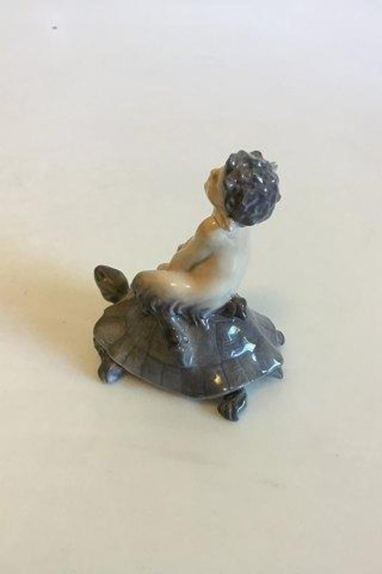 Royal Copenhagen figurine of faun on turtle No 858. 

Measures 9.5 cm / 3 47/64 in.