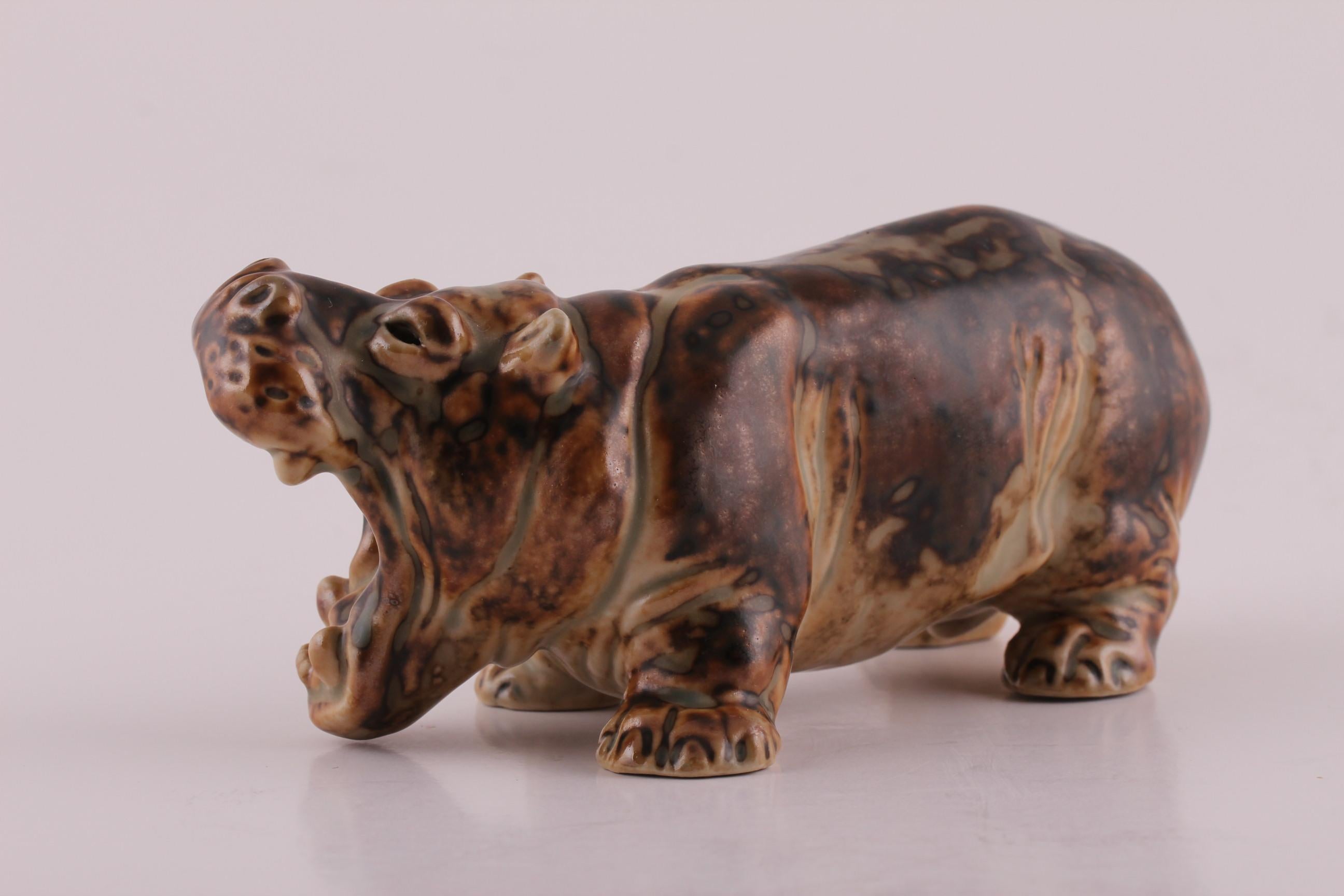 Danish stoneware figurine of a happy hippopotamus designed by Knud Kyhn (1880-1969) and manufactured by Royal Copenhagen. The design was first launched in 1930.

The figurine is decorated with a light and dark-brown Sung glaze. The Sung glaze was