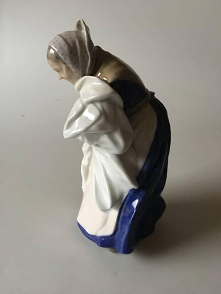 Royal Copenhagen Figurine Old woman with Washing #1043. Designed by Christian Thomsen. Measures 19cm x 10cm and is in good condition.