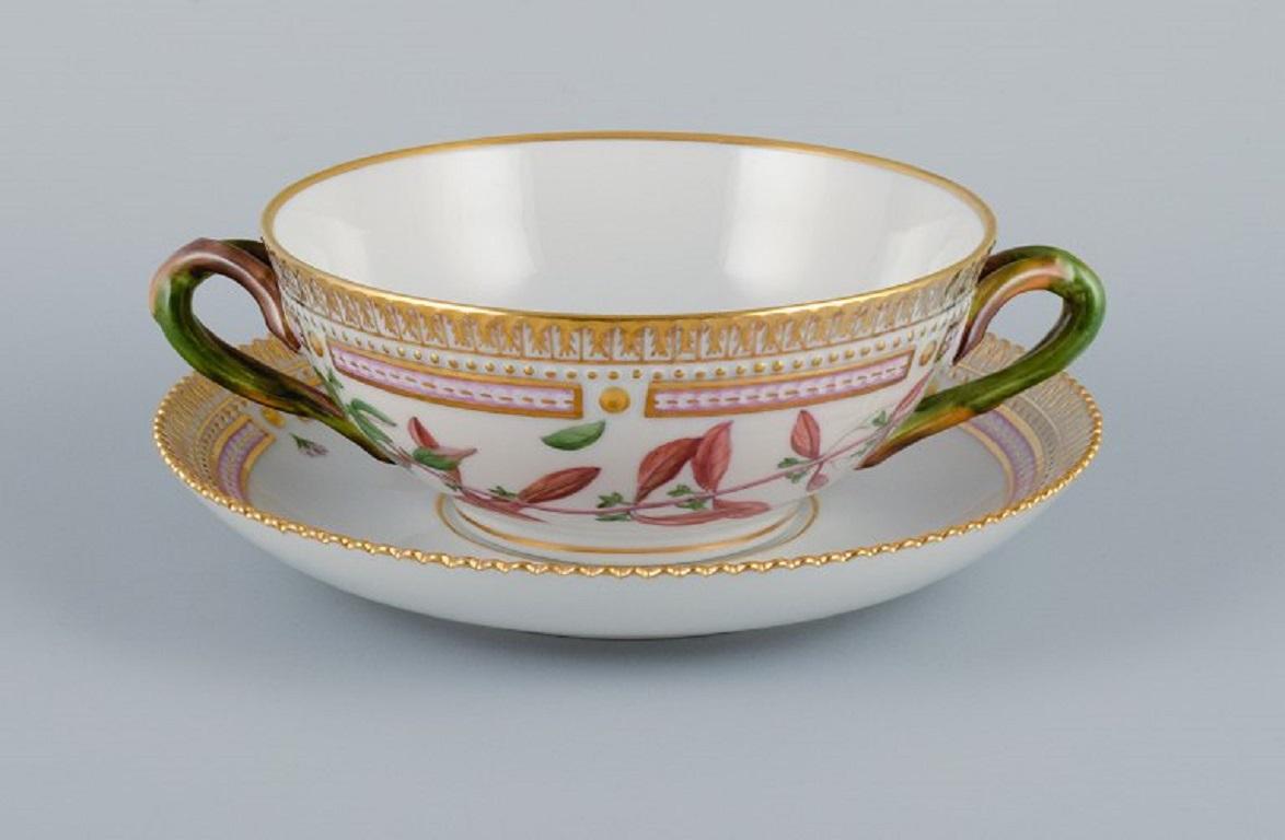 Royal Copenhagen Flora Danica bouillon cup with saucer in hand-painted porcelain with branch-shaped handles, flowers and gold decoration. 
Provenance: Valdemars Castle
Model number 20/3612. 
Cup dimensions: 13 x 5,5 cm.
Saucer diameter: 17