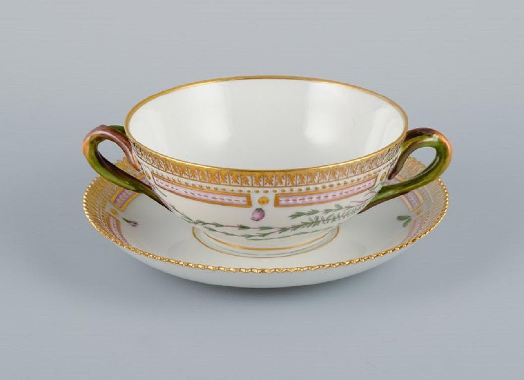 Royal Copenhagen Flora Danica bouillon cup with saucer in hand painted porcelain with branch-shaped handles, flowers and gold decoration. 
Provenance: Valdemars Castle
Cup dimensions: 13 x 5,5 cm.
Saucer diameter: 17 cm.
In excellent condition.