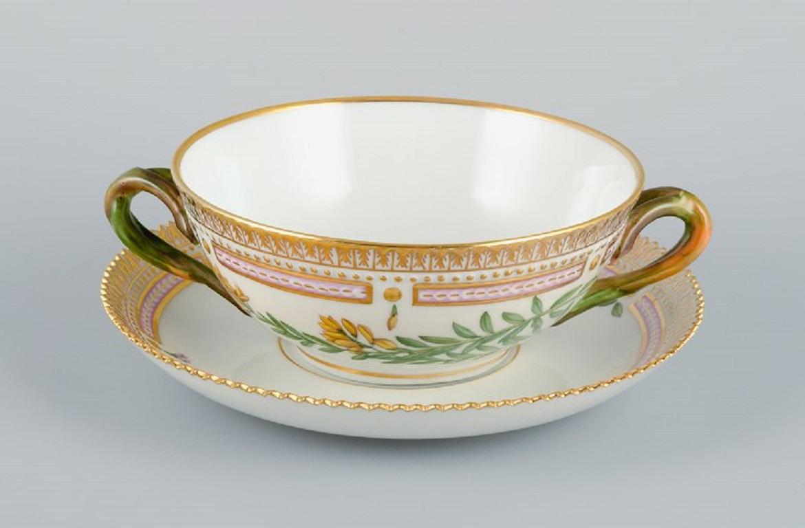 Royal Copenhagen Flora Danica bouillon cup with saucer in hand-painted porcelain with branch-shaped handles, flowers and gold decoration. 
PROVENANCE: VALDEMARS CASTLE
Model number 20/3612. 
Cup dimensions: 13 x 5,5 cm.
Saucer diameter: 17