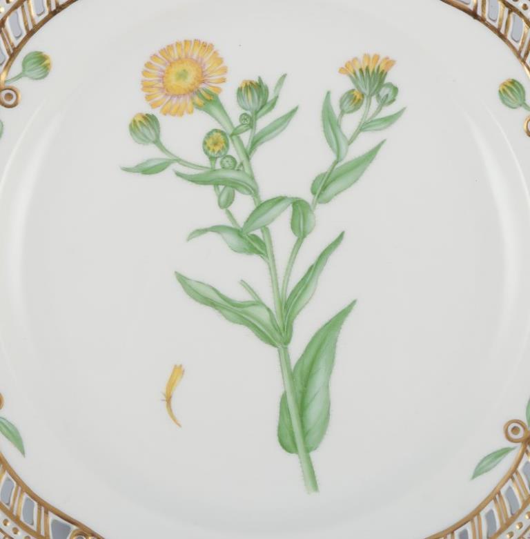 Assiette à déjeuner ajourée Flora Danica de Royal Copenhagen en porcelaine peinte à la main avec des fleurs et des décorations dorées. 
Modèle : 20/3554
Datation : 1958
Nom latin.
En parfait état.
Première qualité d'usine.
Marqué.
Diamètre : 23,0 cm.