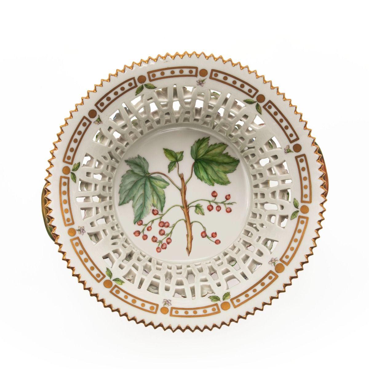 Royal Copenhagen – Flora Danica
Round fruit bowl with openwork lattice and twisted branch handles.
The bowl is decorated with hand-painted flowers on the exterior, a gilded rim, and a detailed central motif of Ribes Rubrum L. (redcurrant) on the