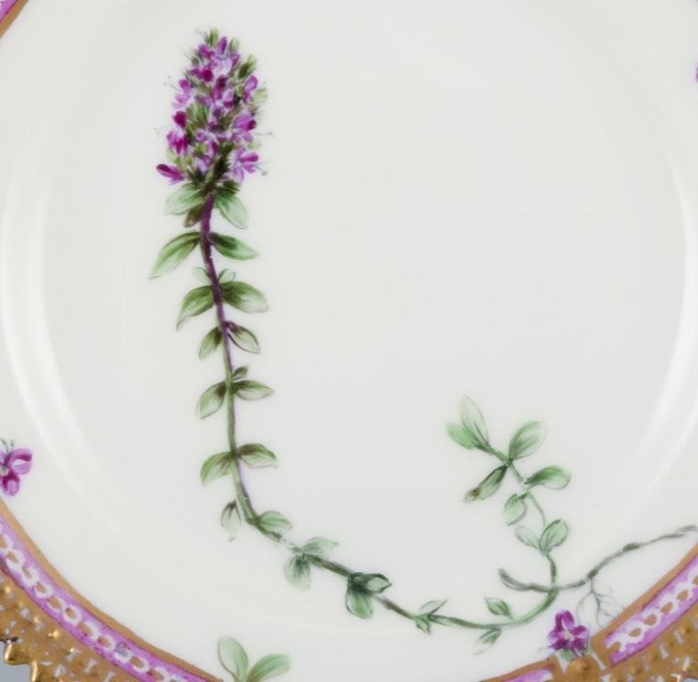 Flora Danica de Royal Copenhagen. 
Plato lateral de porcelana pintada a mano con flores y decoración dorada. 
Pintado fuera de la fábrica.
Citas: Ca. 1920s.
Nombre latino.
En excelente estado.
Segunda calidad de fábrica.
Marcado.
Diámetro: 14,0 cm.