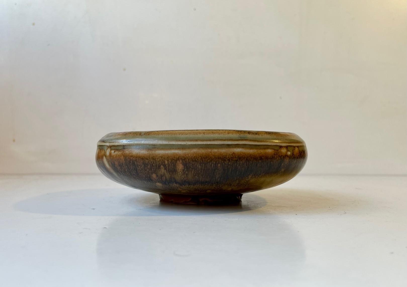 Organically shaped stoneware bowl in earthy Sung and Crystaline Glazes. It was designed by danish ceramist Bode Willumsen and manufactured by Royal Copenhagen in the late 1940s. Early on in his career Bode Willumsen took Axel Salto under his wings