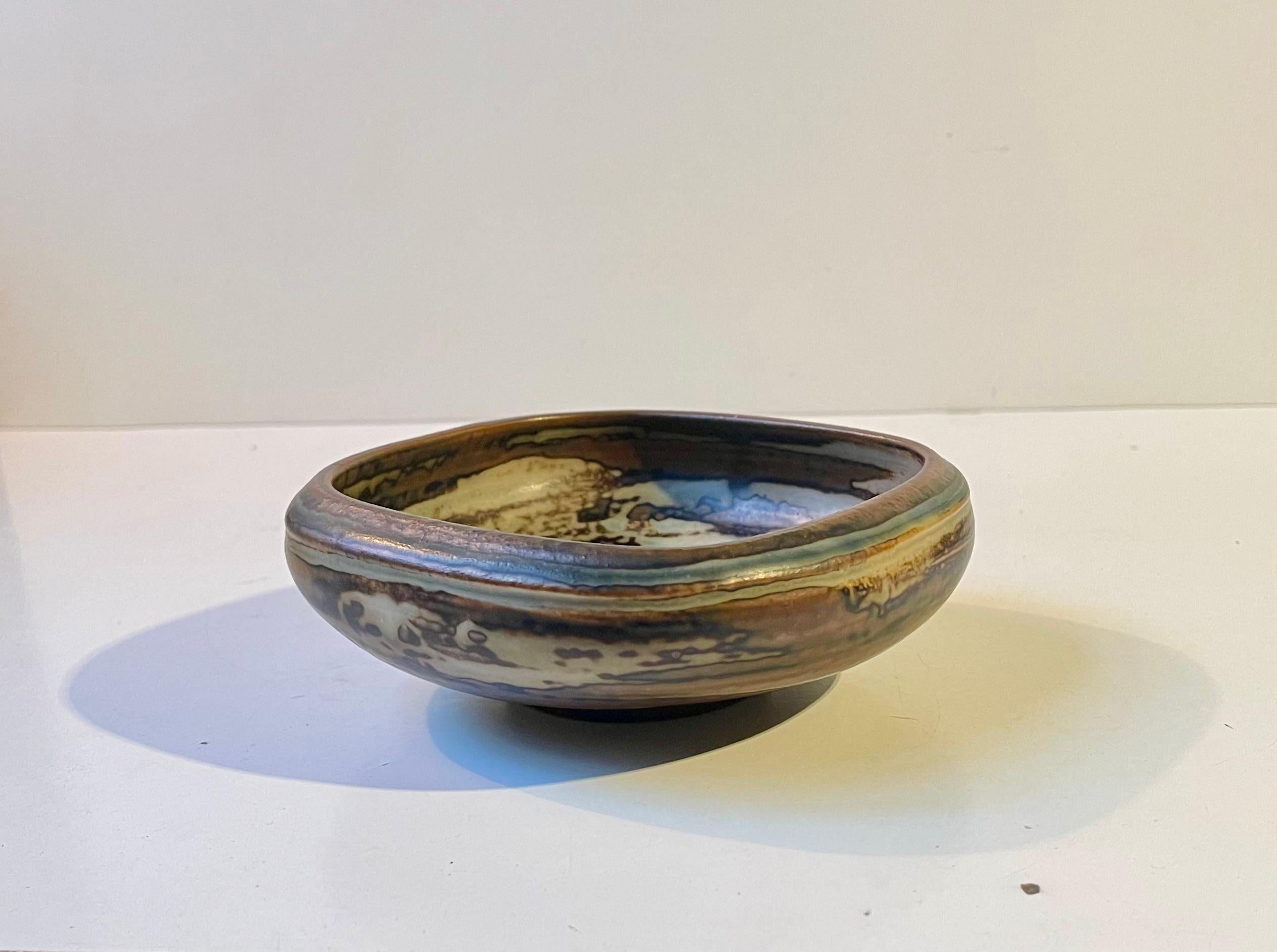 Organically shaped stoneware bowl in earthy Sung and Crystaline Glazes. It was designed by danish ceramist Bode Willumsen and manufactured by Royal Copenhagen in the late 1940s or early 50s. Bode Willumsen was the mentor of Axel Salto who took him