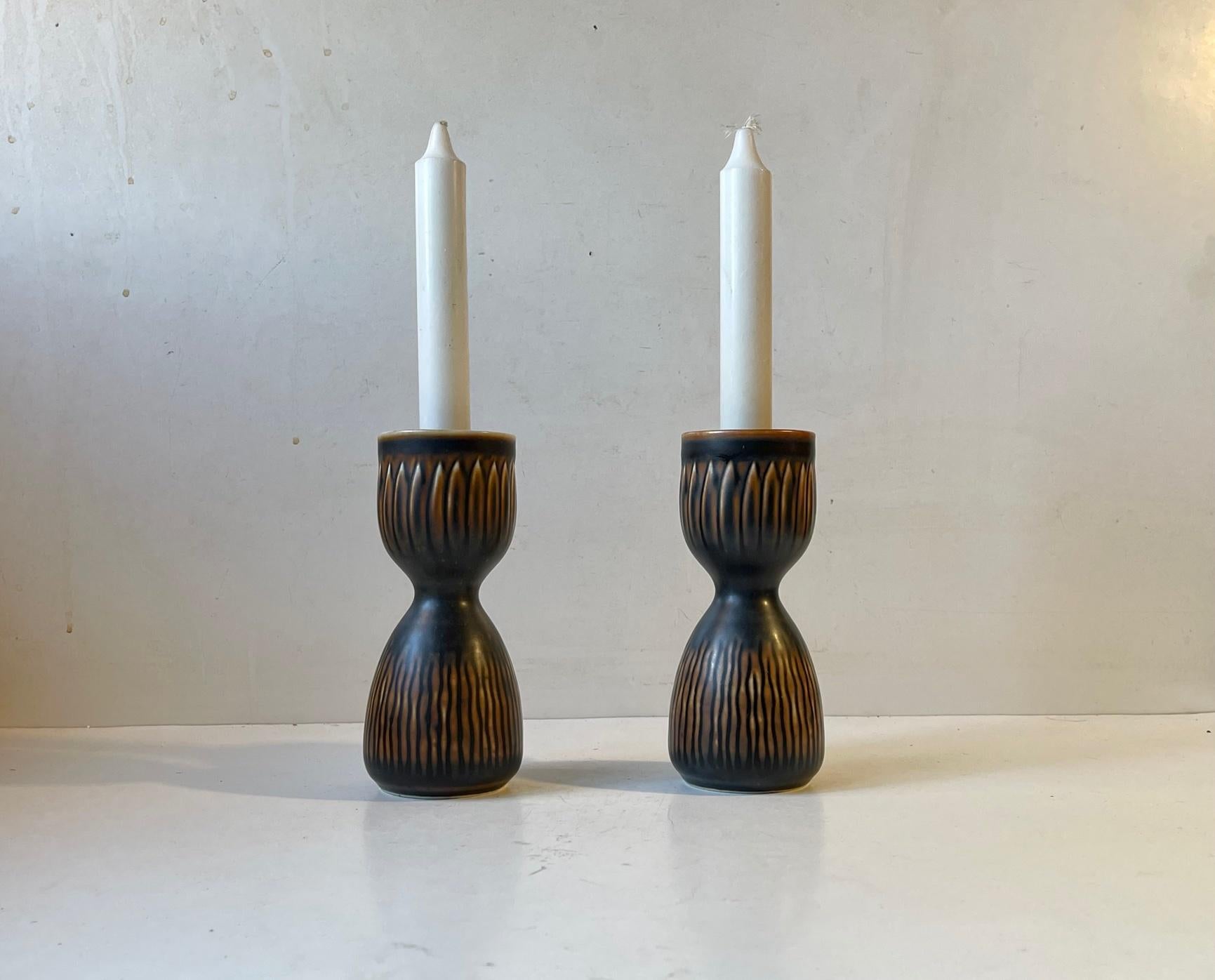 Rare Axel Salto inspired pieces from Royal Copenhagen. Hour Glass Shaped Stoneware Vases or candlesticks designed by Gerd Bogelund during the 1950s or early 60s. Decorated with a dark brown almost black main glaze and featuring abstract/floral