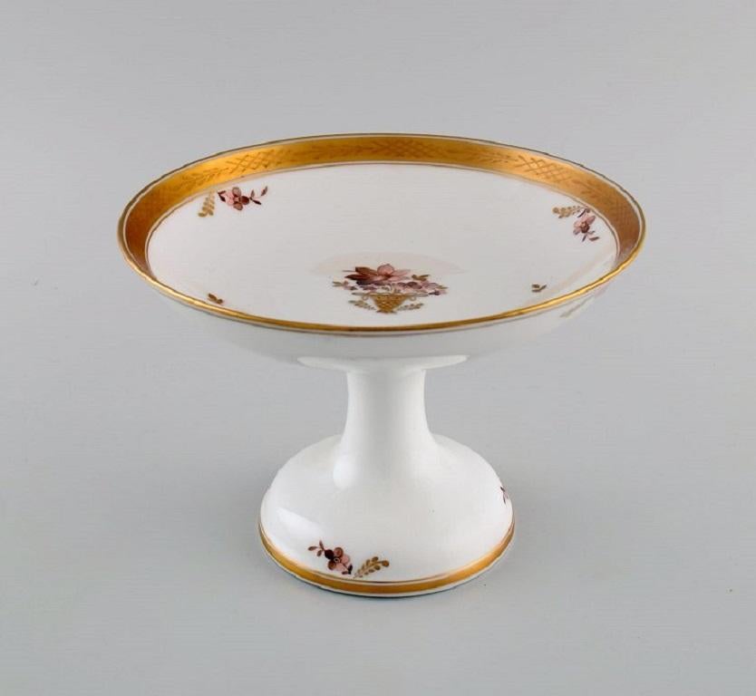 Royal Copenhagen Golden basket compote in porcelain with flowers and gold decoration. Model number 595/9410. 
Early 20th century.
Measures: 20 x 14 cm.
In excellent condition.
Stamped.
1st factory quality.