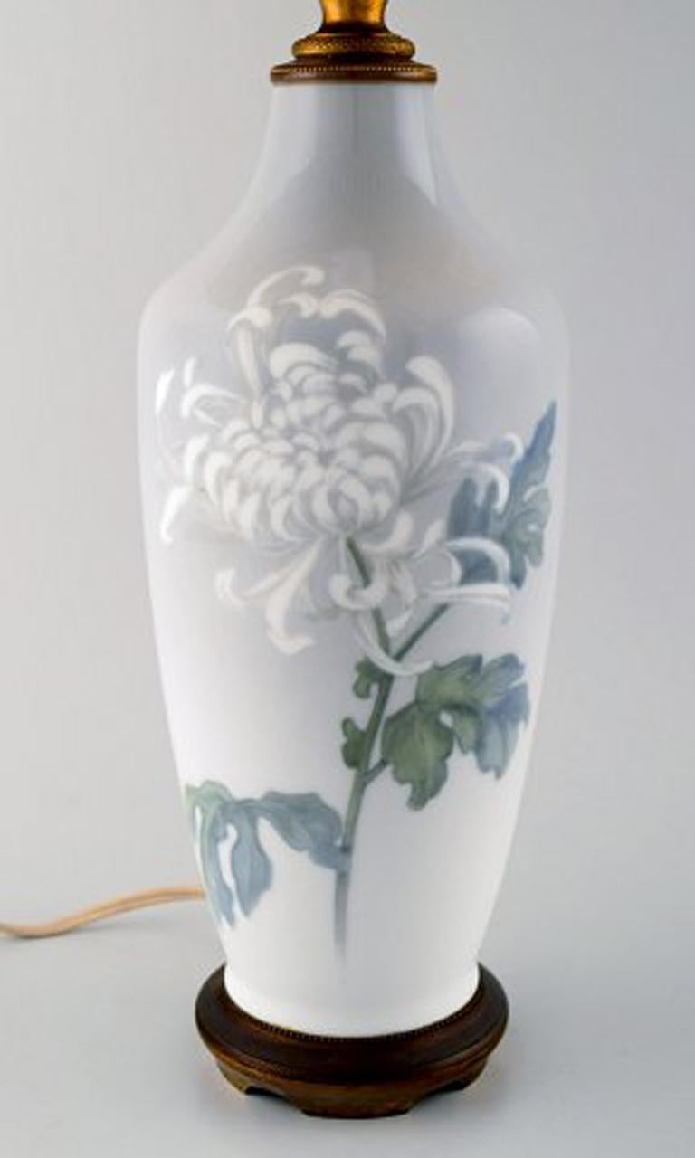 Royal Copenhagen large table lamp on brass stand decorated with flowers. 1930's. Le Klint screen.
In very good condition.
Stamped. 
1st factory quality.
Total height 55 cm. Diameter of lamp: 14 cm.