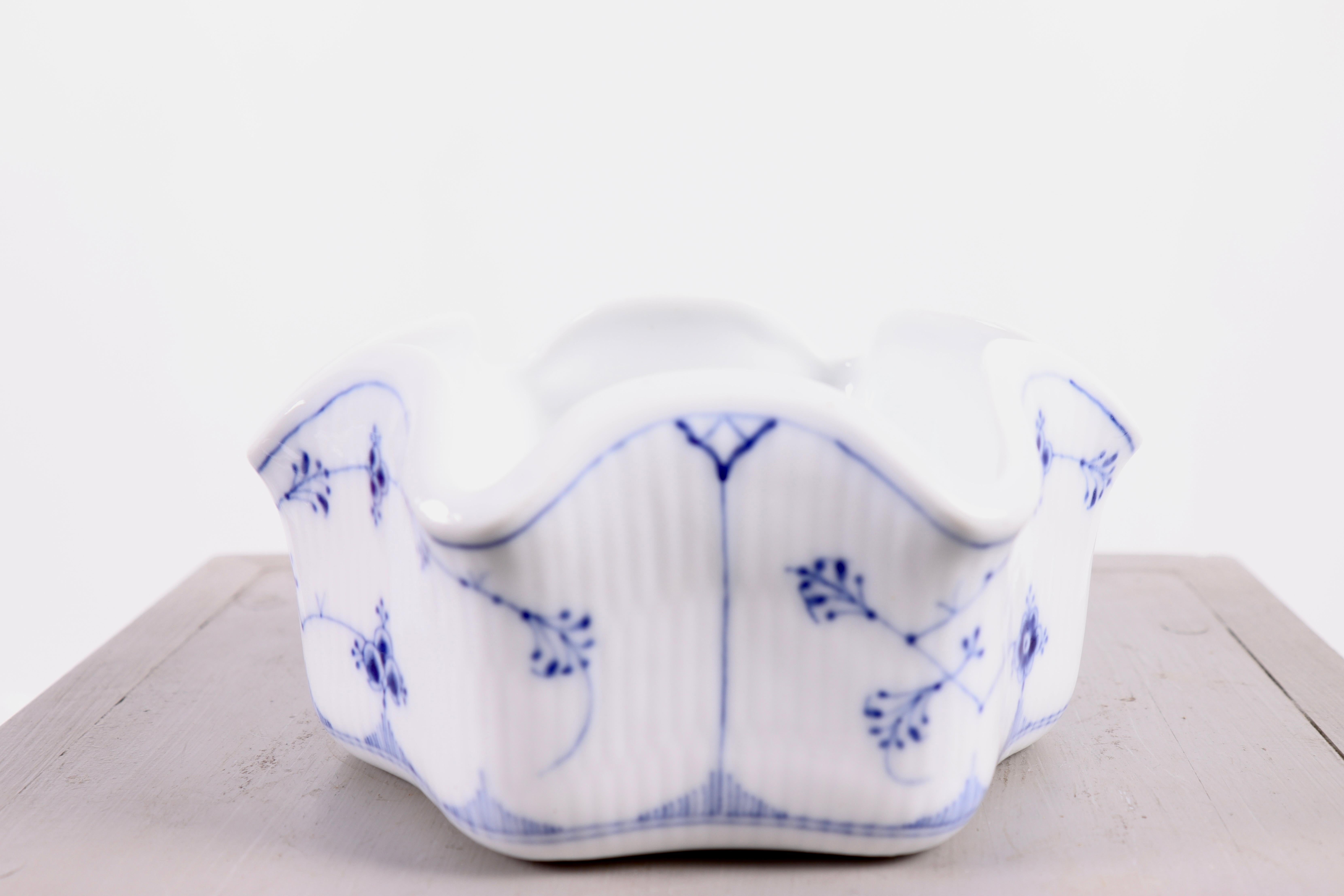 Un élégant et unique bol cannelé bleu de Royal Copenhagen, modèle 471, conçu pour contenir six coquetiers. Cette coupe a été fabriquée entre 1898 et 1923.

Le bol est orné du motif caractéristique Blue Fluted, composé de délicates fleurs et branches