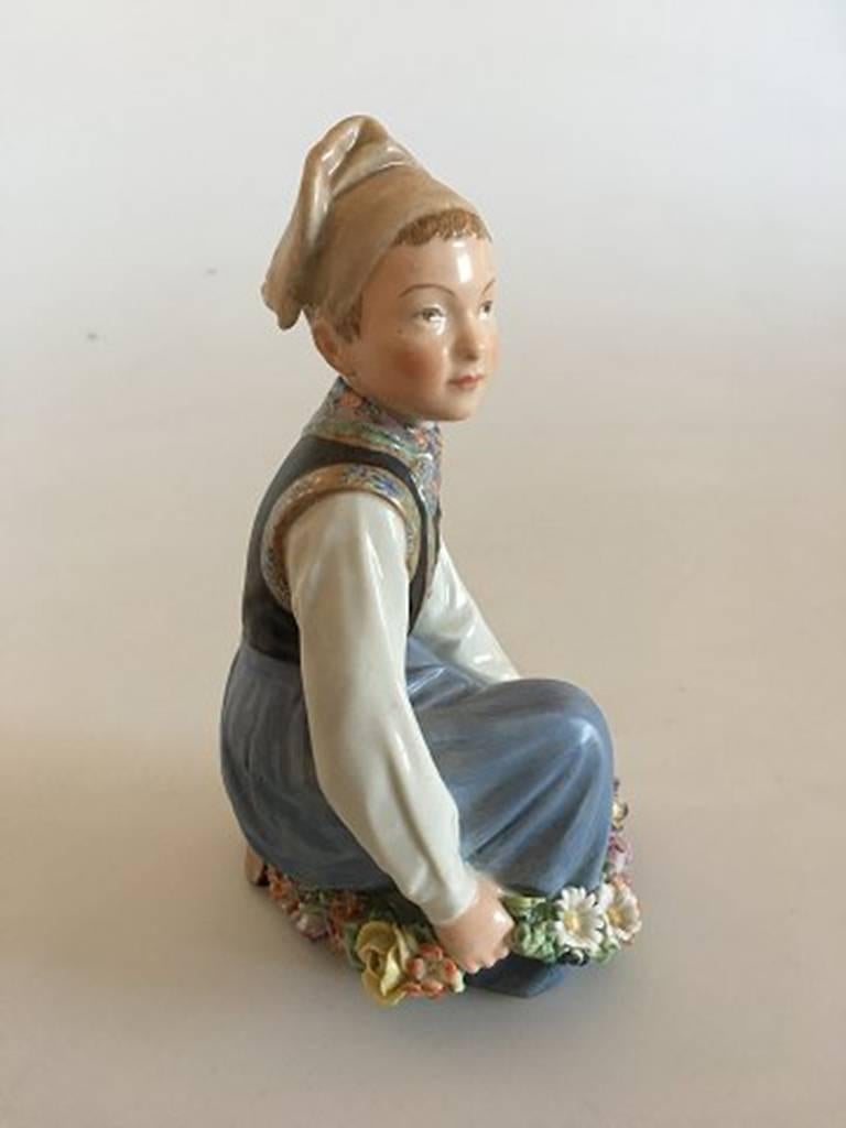 Royal Copenhagen over-glaze figurine Amager boy #12414. Measures: 15cm and has minimal chips on flowers.