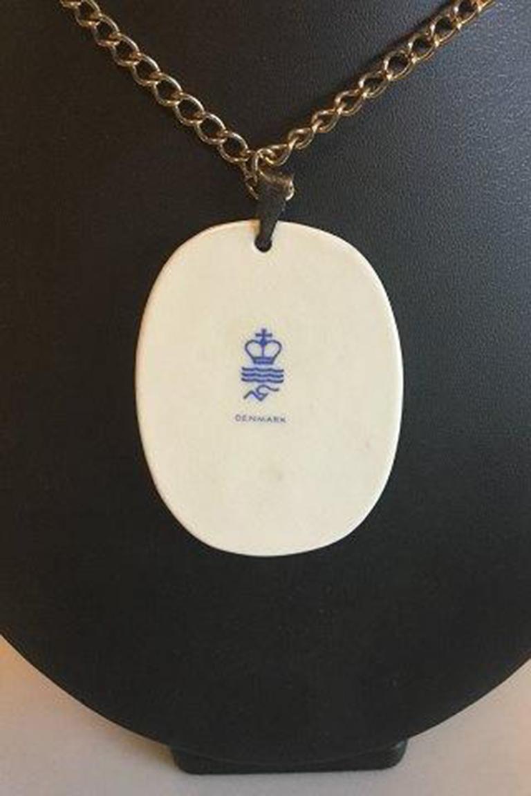 Royal Copenhagen pendant of porcelain designed by Nils Thorson. Sterling silver by Anton Michelsen.

Measures Pendant: 6 cm / 2 23/64 in. Chain: 60 cm / 23 5/8 in.