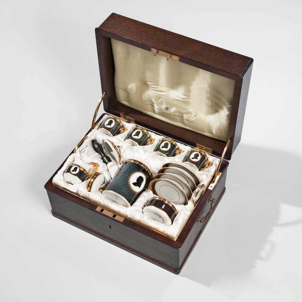 A Royal Copenhagen porcelain coffee service, in its original wood and silk- lined presentation travel box, comprising a coffee pot, four coffee cups and saucers, a creamer, a covered sugar bowl and a tray, each with white ground and black and gilt