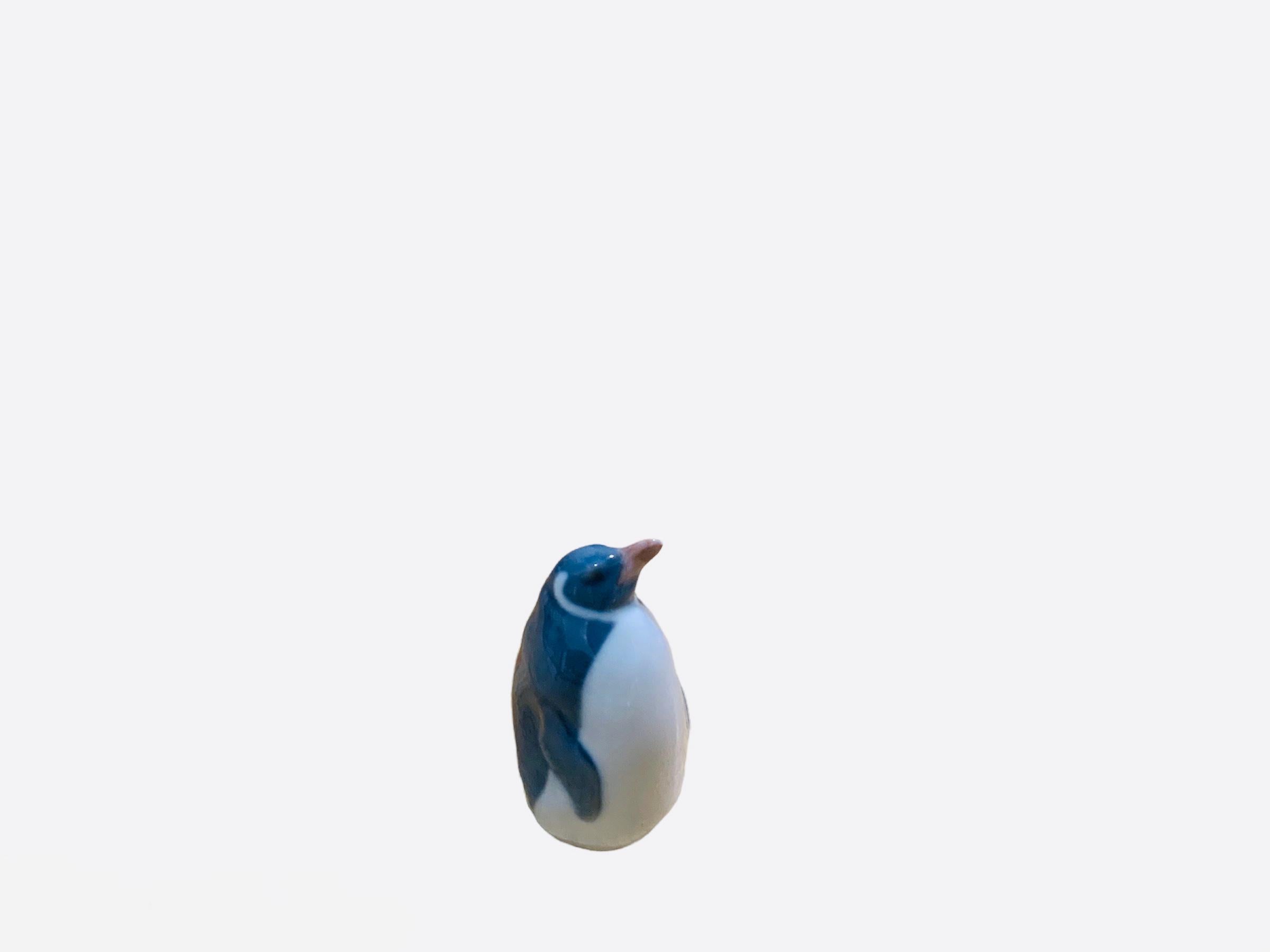 This is a Royal Copenhagen porcelain of small sharp and proud bird figurine known as a penguin. At the base is the Royal Copenhagen hallmark with the number-3003, a crown and Denmark. It is hand painted white, blue and grey.