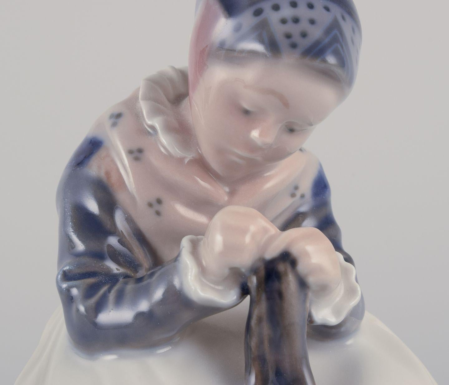 Royal Copenhagen porcelain figurine. Amager girl in traditional dress knitting. Porcelana en venta