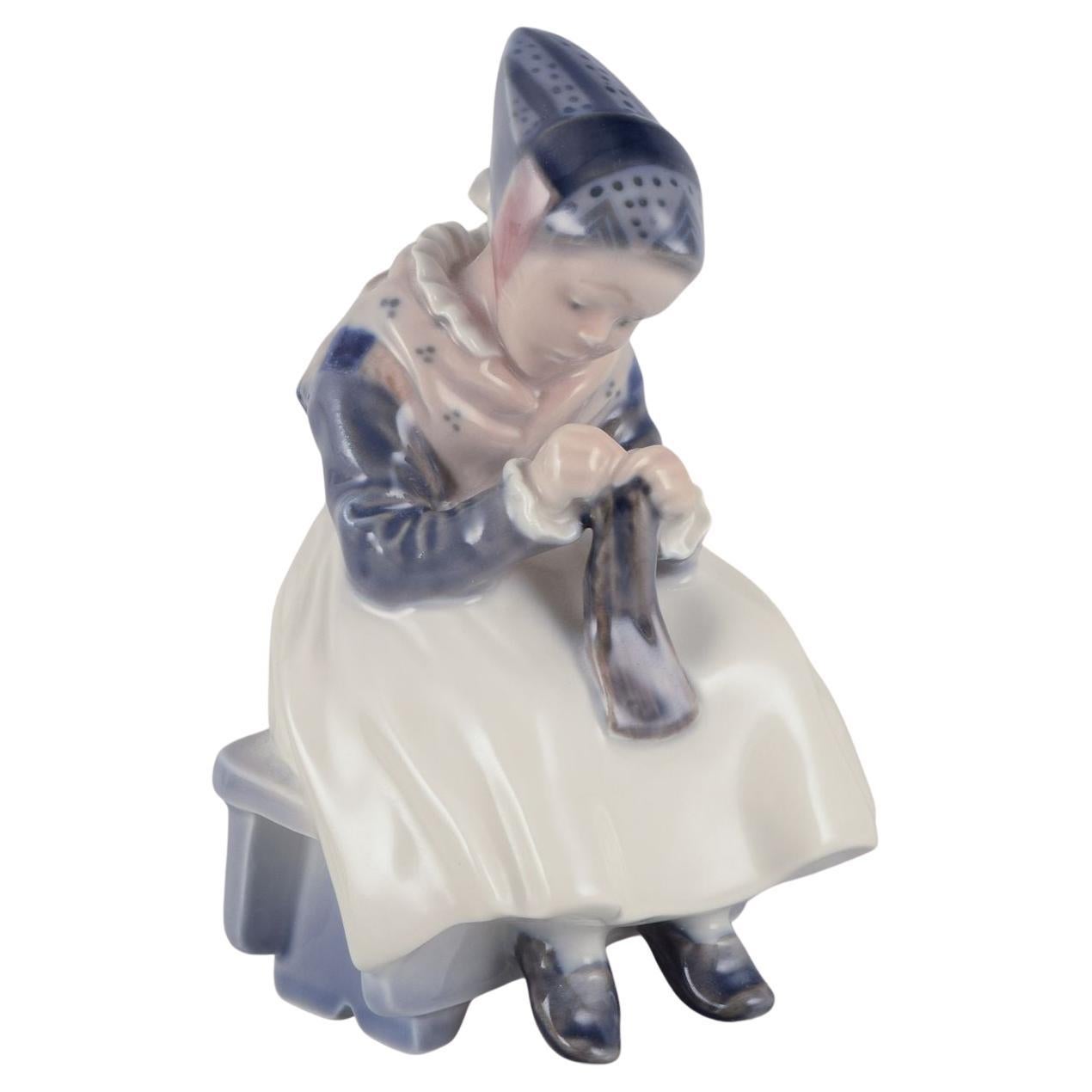 Royal Copenhagen porcelain figurine. Amager girl in traditional dress knitting.