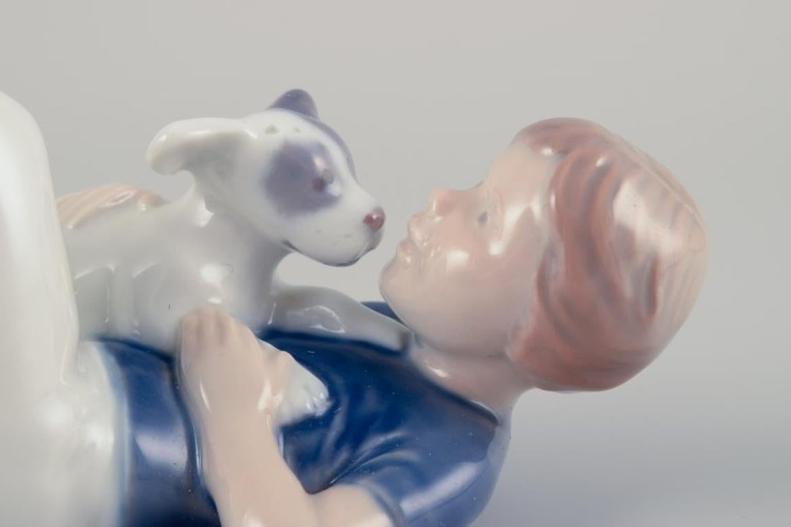 Metà XX secolo Royal Copenhagen. Statuetta in porcellana di un ragazzo con un cucciolo. Rara statuetta. in vendita