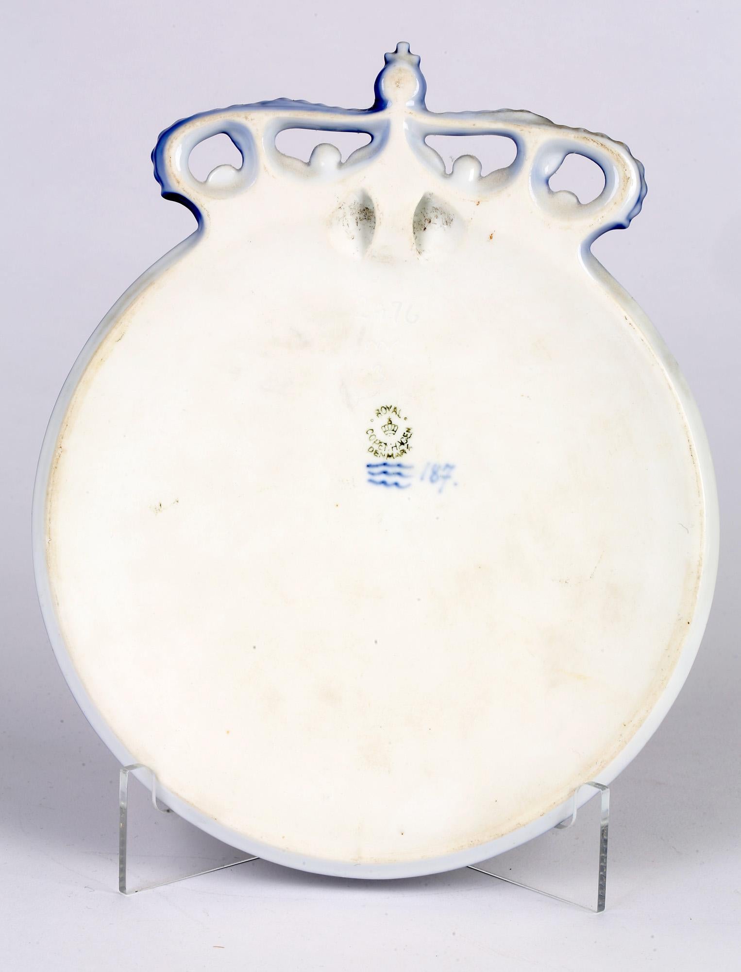 An unusual and scarce Danish porcelain commemorative plaque made by Royal Copenhagen and made between 1893 and 1928. The plaque is of rounded shape with a slightly domed front with a molded crown to the top edge and set within a molded raised bead