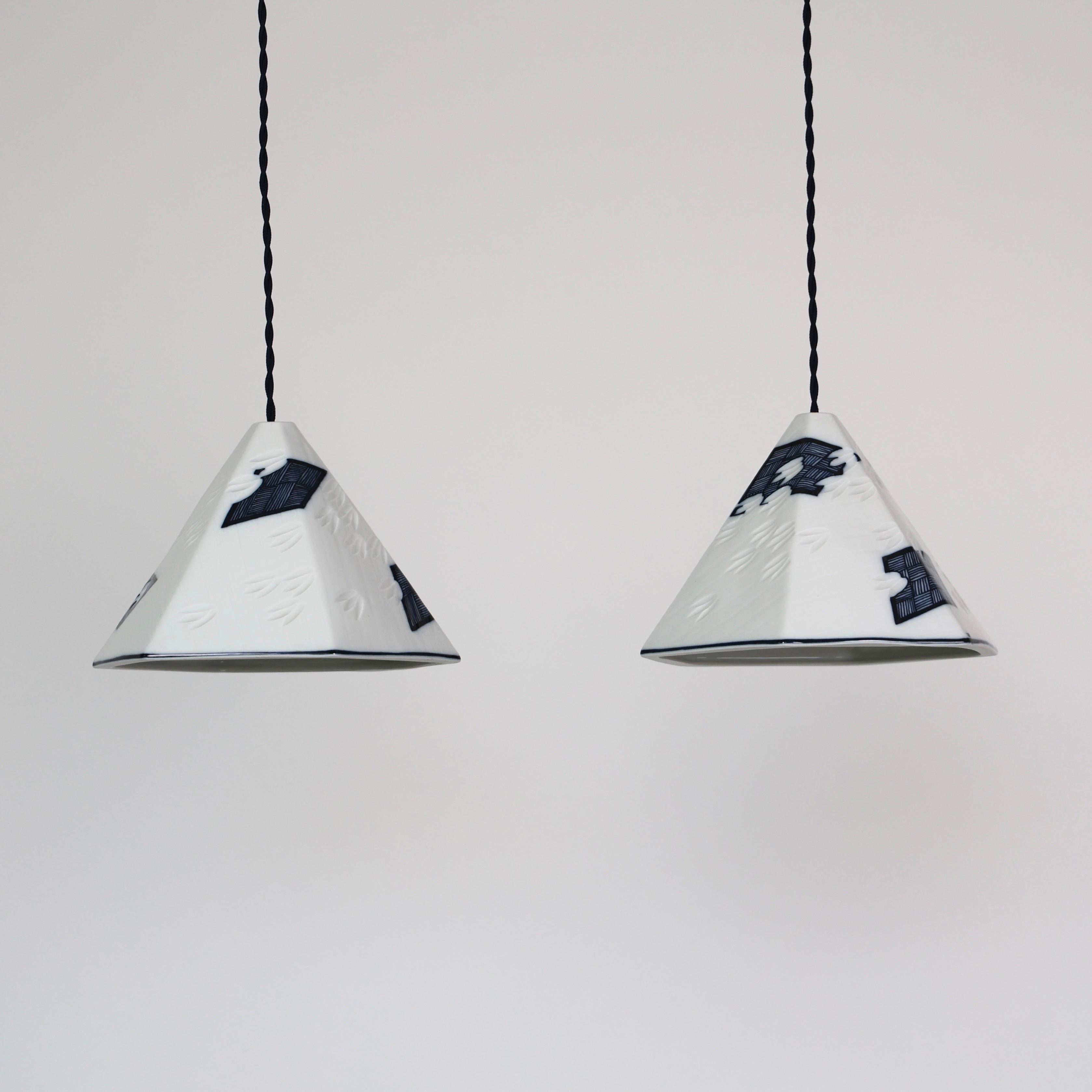 Elegant set of Royal Copenhagen Porcelain Pendant Lights designed by Anne Marie Trolle in the 1980s. 

* Set (2) of white 6-sided porcelain pendant lights with dark blue drawings 
* Designer: Anne Marie Trolle
* Model: Luciana (small)
* Producer: