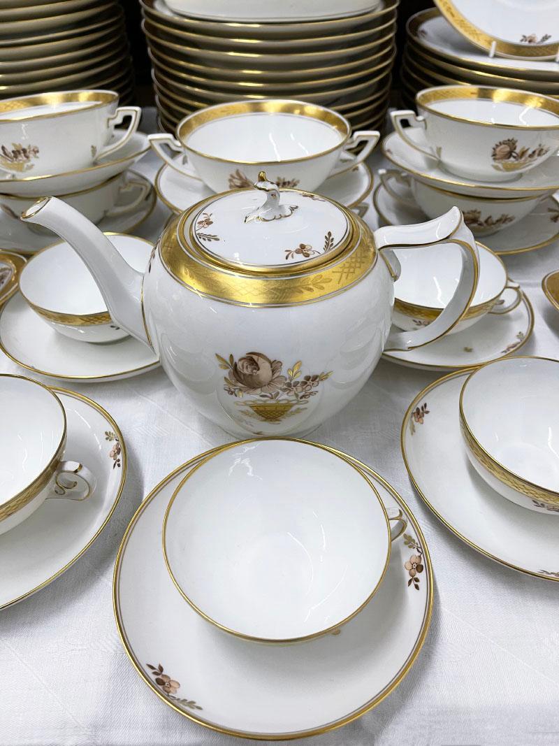 Royal Copenhagen porcelain tableware dinner service, Denmark 1961

A Royal Copenhagen porcelain dinner service with pattern number 595, the floral golden basket 
Flowers in the centre with gold pattern trim
A small paper book in cover with 