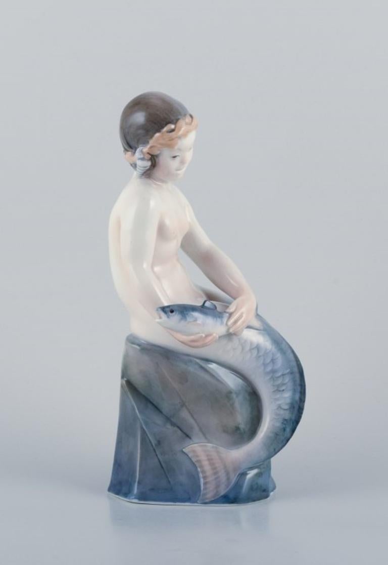 Royal Copenhagen, seltene Porzellanfigur einer Meerjungfrau mit Fisch in den Händen.
Modell: 2412.
Ungefähr 1930.
Markiert.
Zweite Fabrikqualität.
In ausgezeichnetem Zustand.
Abmessungen: Breite 12,0 cm, Höhe 26,7 cm.