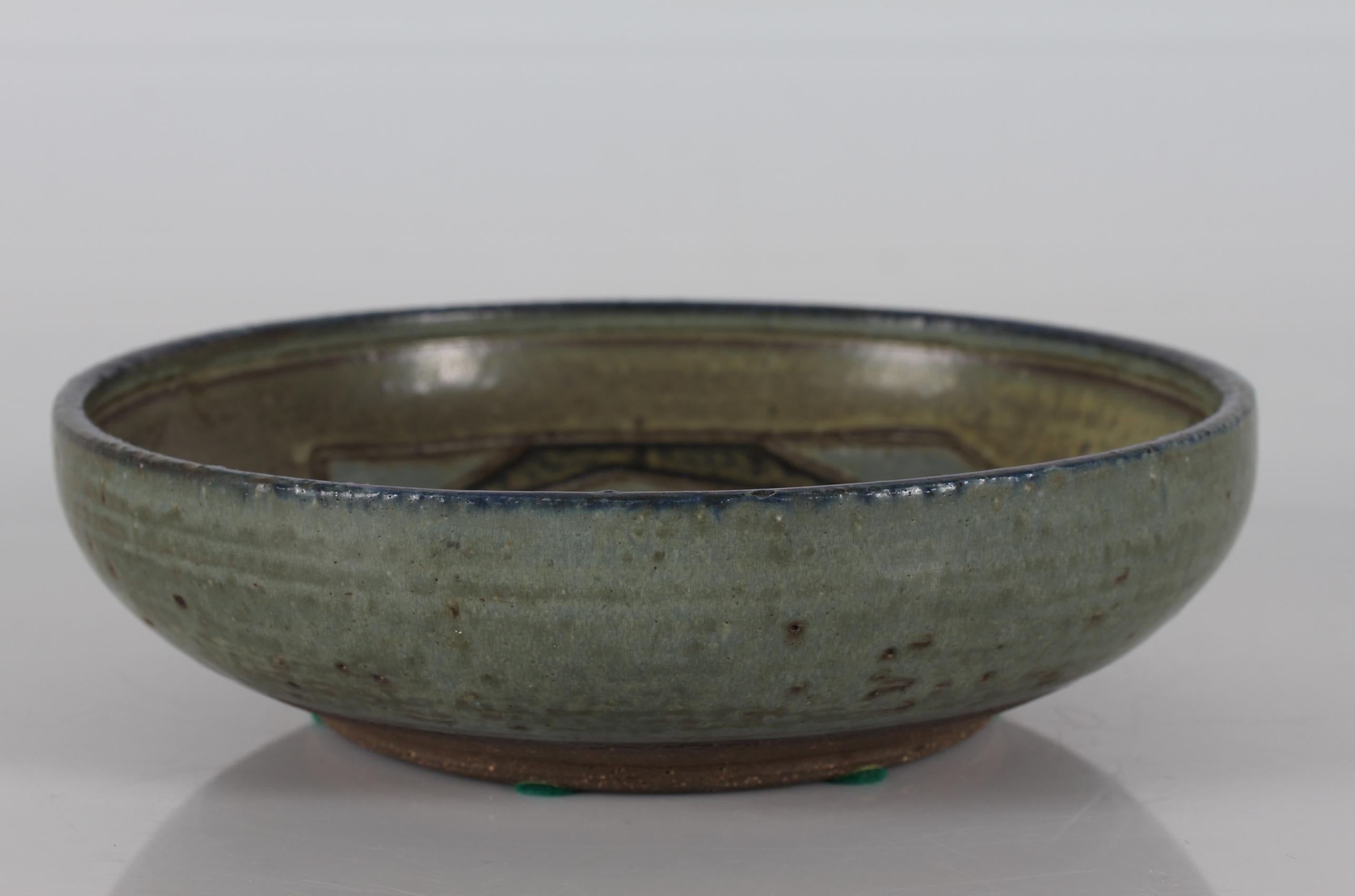 Round stoneware bowl with bird motif designed by Danish ceramist Jørgen Mogensen and manufactured by Royal Copenhagen in Denmark:
The bowl has a grey, blue and brown glaze and is signed with 3 waves for Royal Copenhagen and the monogram JM for