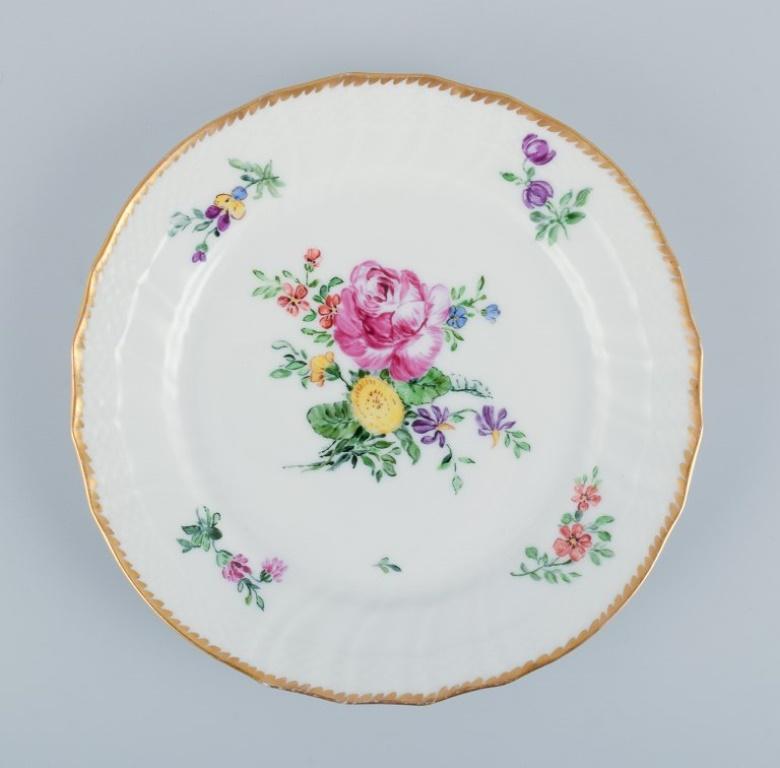 Royal Copenhagen, Saxon Flower, ein Teller und eine niedrige Schale, handdekoriert mit polychromen Blumen und einem Goldrand.
Die Platte ist zweite Fabrikqualität und außerhalb der Fabrik dekoriert. 
Datiert 1933.
Die Schale ist erste