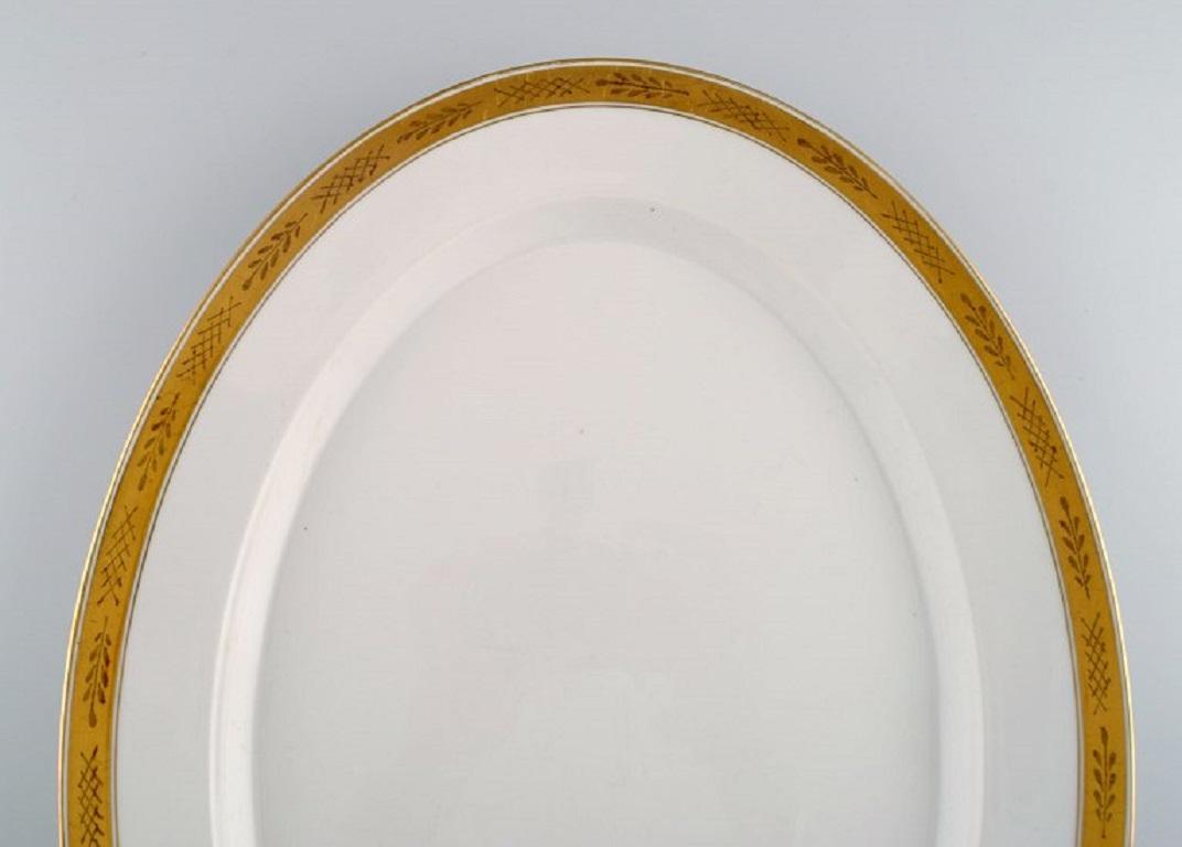 Royal Copenhagen service no. 607. 
Colossal serving dish in porcelain. Gold border with foliage. 
Model number 607/9592. 
Dated 1943.
Measures: 47 x 35 cm.
In excellent condition.
Stamped.
1st factory quality.