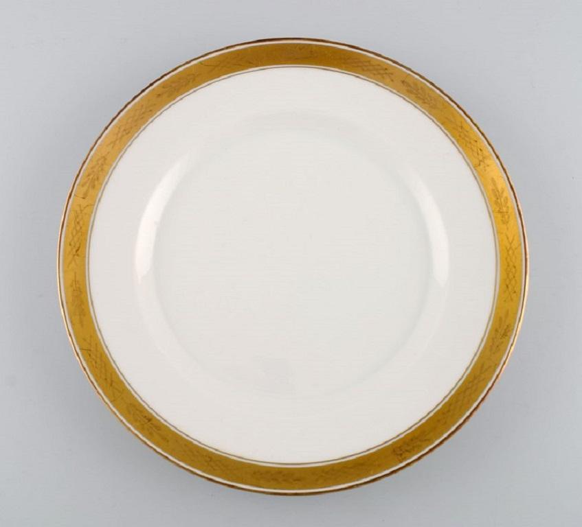 Royal Copenhagen service no. 607. 
Eight porcelain dinner plates. Gold border with foliage. Model number 607/9586. Dated 1944.
Diameter: 25 cm.
In excellent condition.
Stamped.
1st Factory quality.
