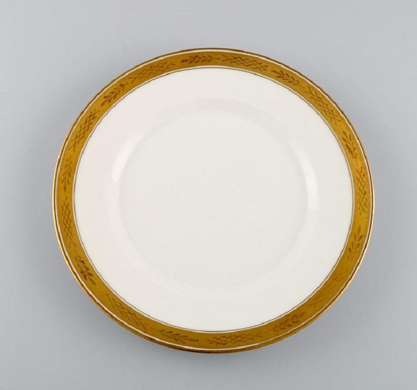 Royal Copenhagen service no. 607. 
Nine porcelain lunch plates. Gold border with foliage. Model number 607/9589. 
Dated 1946.
Diameter: 22 cm.
In excellent condition.
Stamped.
1st factory quality.