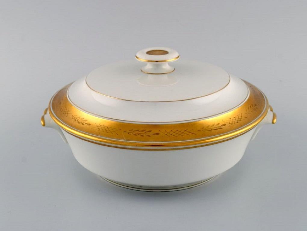 Royal Copenhagen service no. 607. Porcelain lidded tureen. 
Gold border with foliage. Model number 607/9575. Dated 1944.
Measures: 24.5 x 12 cm.
In excellent condition.
Stamped.
1st factory quality.