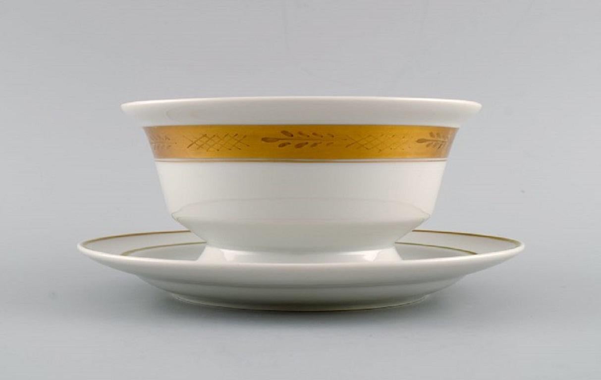 Royal Copenhagen service no. 607. Porcelain sauce bowl. 
Gold border with foliage. Model number 607/9580. Dated 1944.
Measures: 20 x 9 cm.
In excellent condition.
Stamped.
1st factory quality.