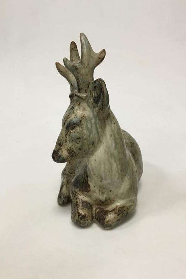 Royal Copenhagen stoneware figurine of resting deer no 20507. Knud Kyhn. 

Measures 25 cm (9 27/32 in.).
 