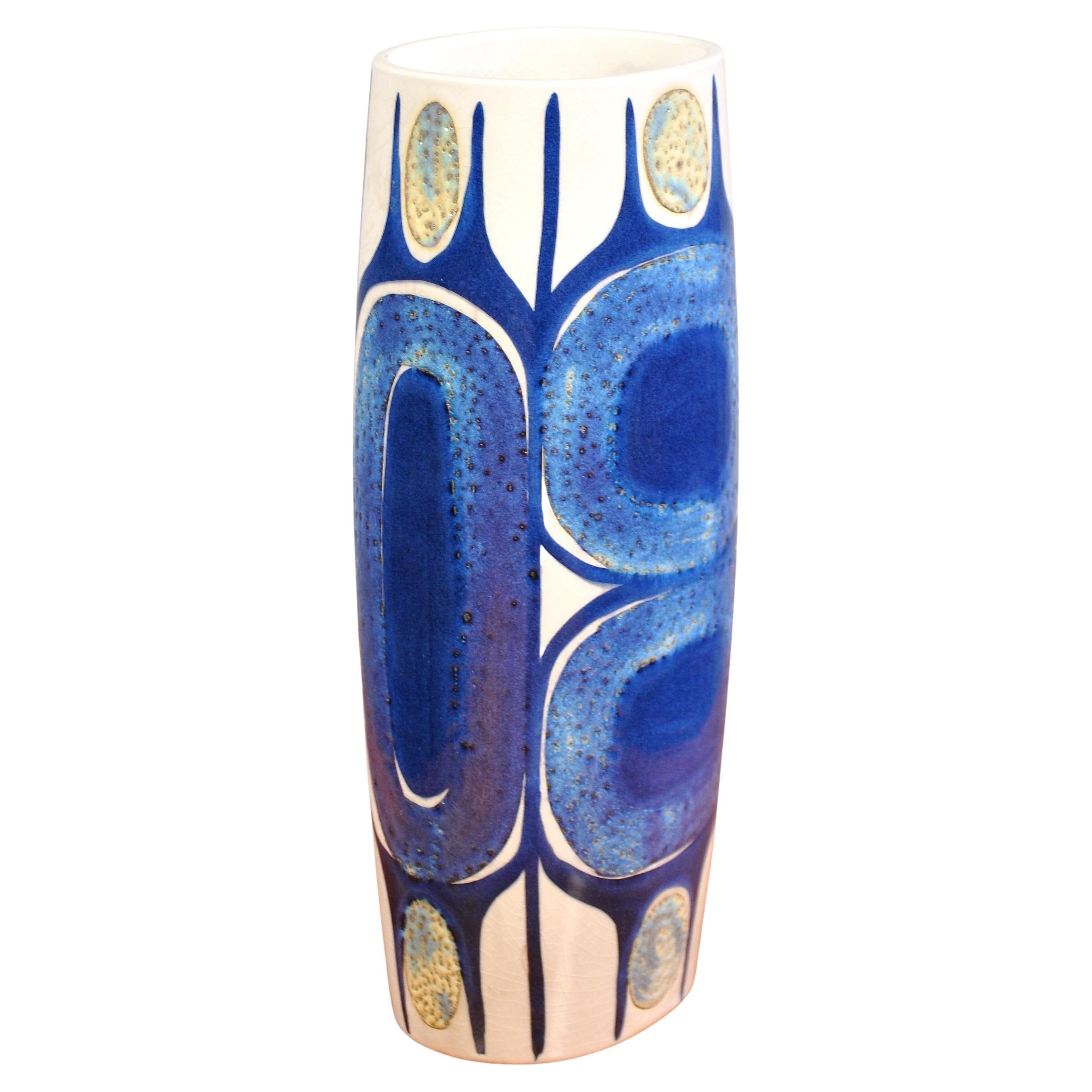 This exquisite Danish Modern vase from the Tenera line by Royal Copenhagen (Aluminia) was designed by Inge-Lise Koefoed in the 1960s. The glazed ceramic vase features hand-painted motifs in shades of deep blue, purple, and shimmering pale yellows or