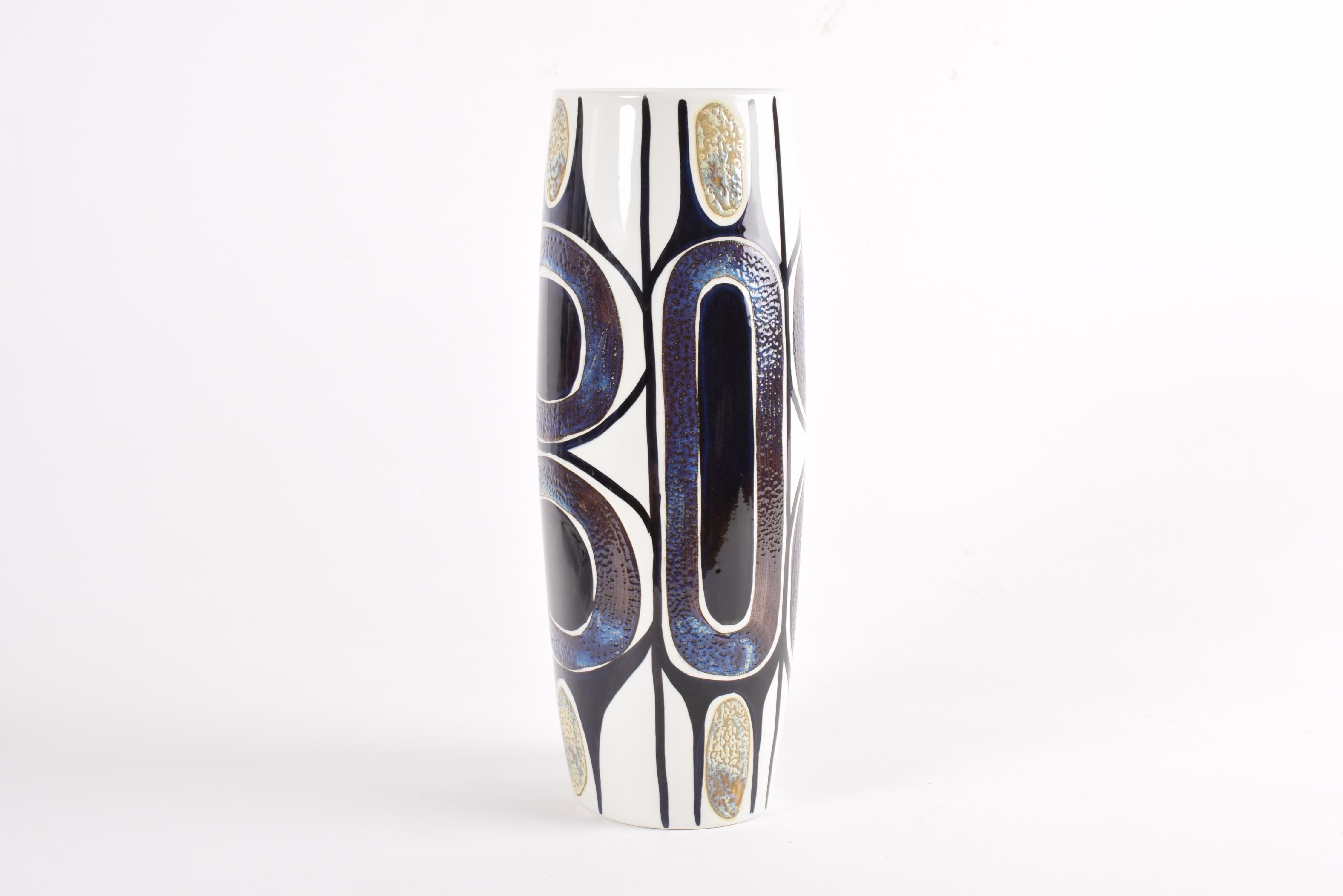 Tall and eye-catching vase from the Royal Copenhagen Tenera series.
The bold hand painted decor is designed by Inge-Lise Koefoed.
The colors are blue and purple and shimmering pale yellow or gold on white.

The vase was manufactured in the