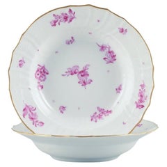 Royal Copenhagen, zwei tiefe Teller, handbemalt mit violetten Blumen und Goldrand.