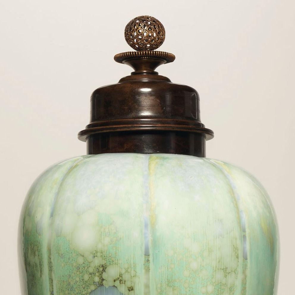 Our extraordinary porcelain vase with cover by Knud Valdemar Engelhardt (Danish, 1882-1931) for Royal Copenhagen dates from circa 1916, and features a unique celedon colored crystalline glaze with abstract blue and white flower heads and patinated