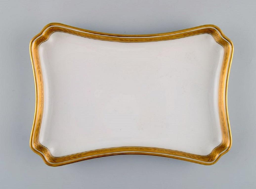 Royal Copenhagen white dagmar. Sugar bowl and creamer on serving tray in porcelain with hand-painted gold decoration. 
1930s.
The tray measures: 23.5 x 16.5 cm.
The sugar bowl measures: 12.5 x 10 cm.
In excellent condition.
Stamped.
1st