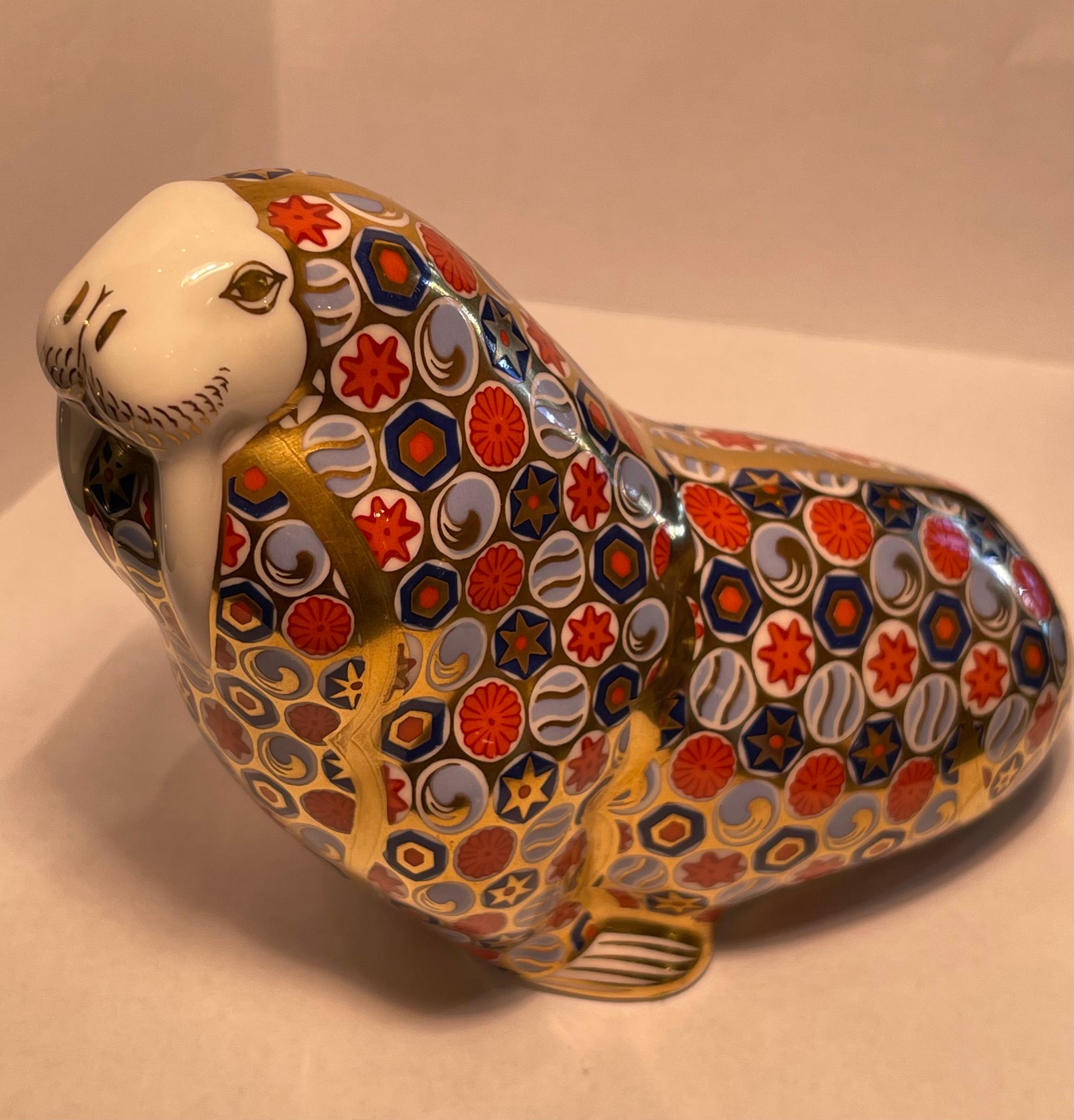 Very collectible, hand-made and hand-painted in England, retired Royal Crown Derby fine bone china walrus figurine or paperweight. The walrus is richly and elaborately decorated in rust, cobalt blue, periwinkle and accented with 22k gold in the