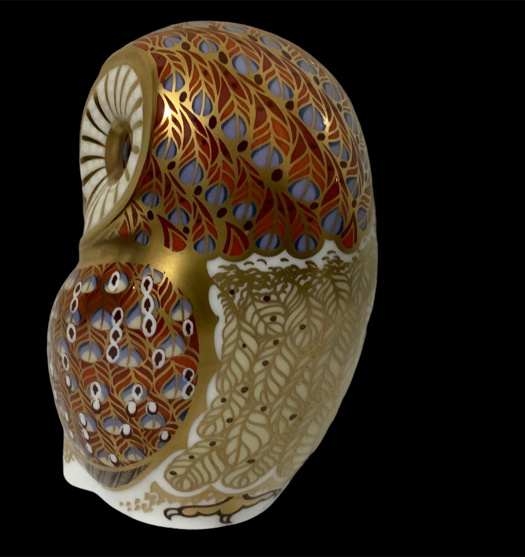 This a Royal Crown Derby porcelain Imari style owl figurine paperweight. It is hand painted in vivid colors of red, different shades of blues and white feathers highlighted by gold. It has very expressive eyes. Below the base, it is the Royal Crown