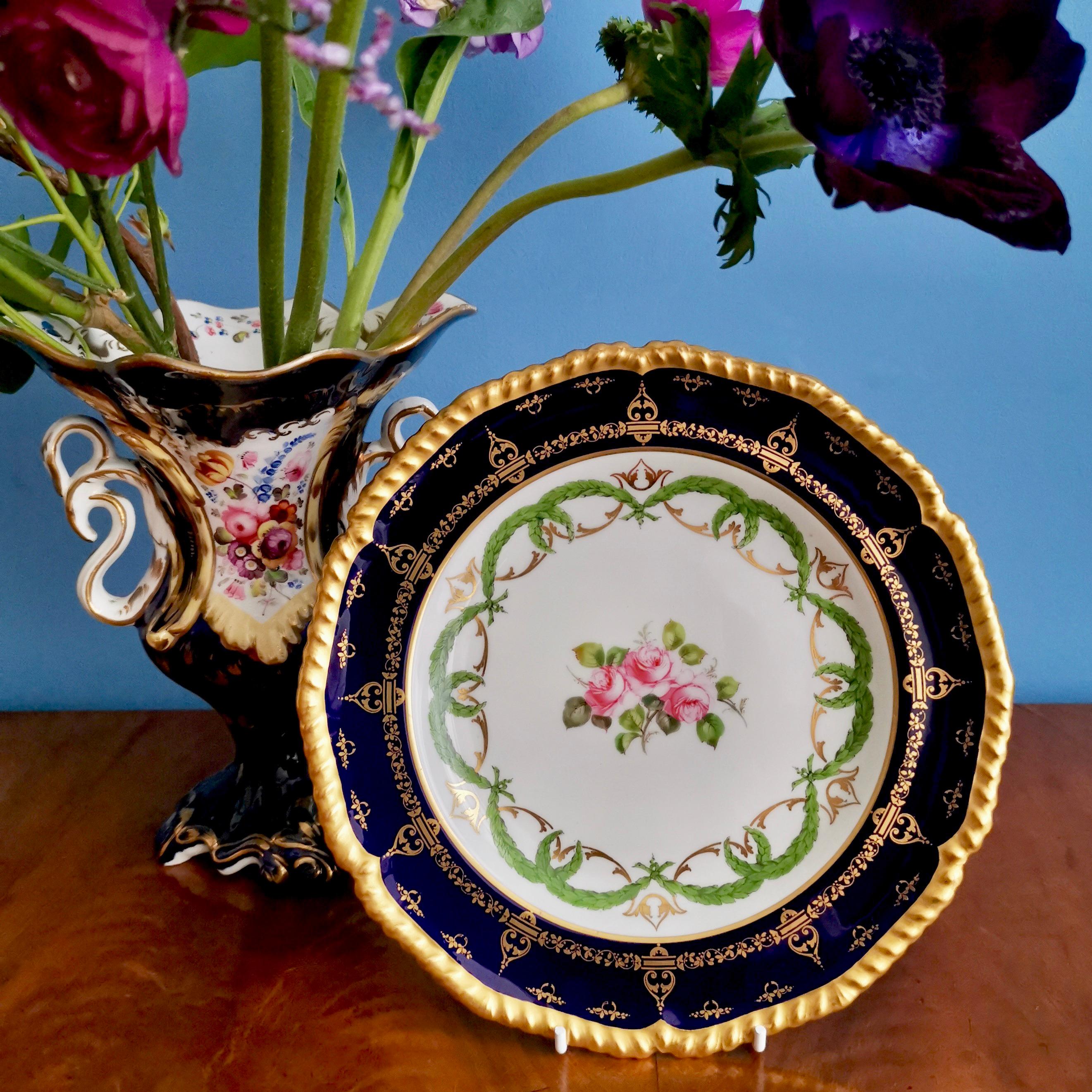 This is a beautiful dessert plate made by Royal Crown Derby in 1907. The plate has a deep cobalt or mazarine blue ground with rich gilt decorations, green garlands and some finely painted Billingsley roses in the centre.

The Derby Porcelain