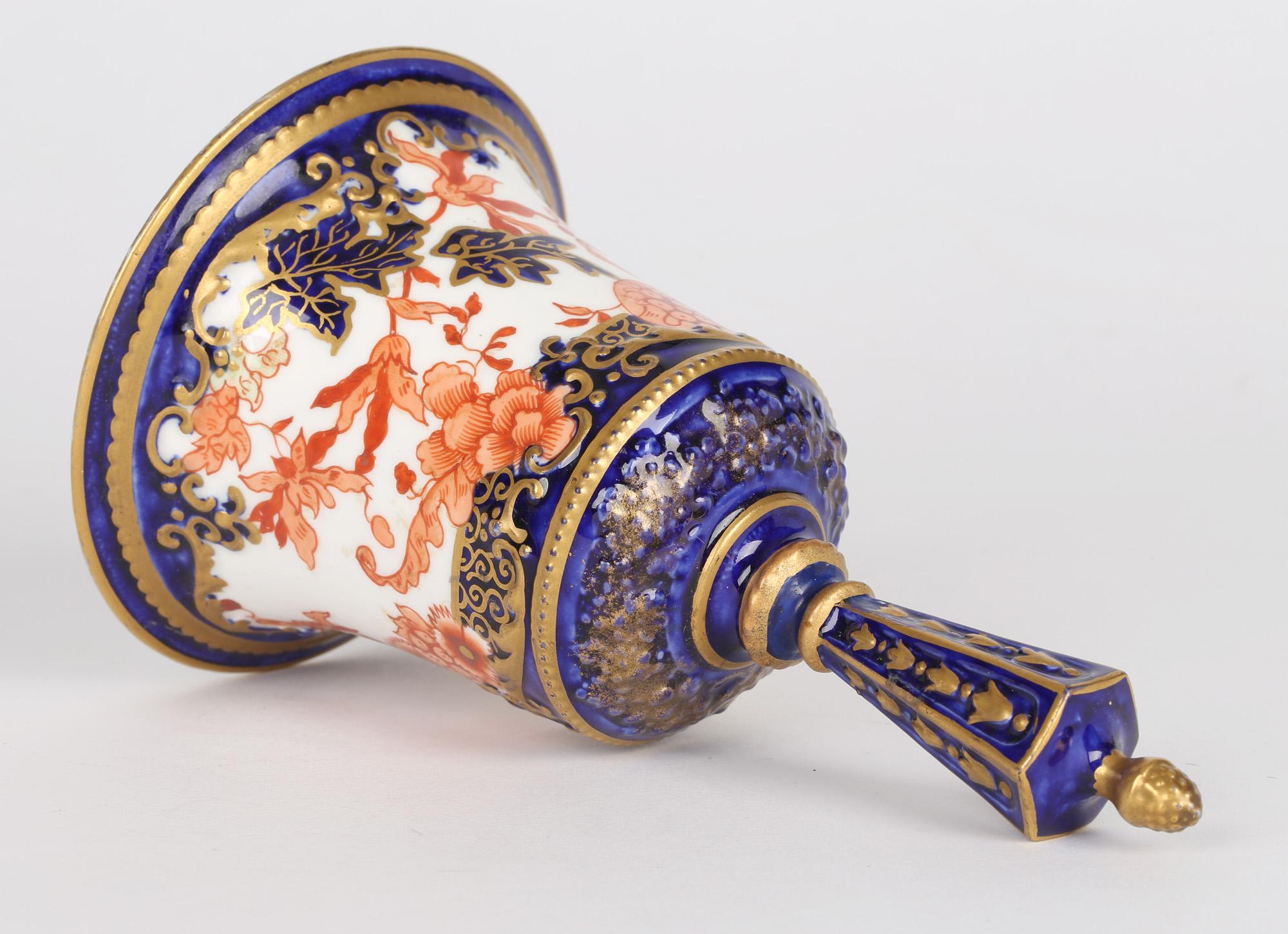 A very rare antique porcelain imari pattern bell by Royal Crown Derby and dating from 1904. The bell has a traditional bell shaped body with molded and finely decorated patterning in tones of red, blue and green highlighted with gilding. The bell