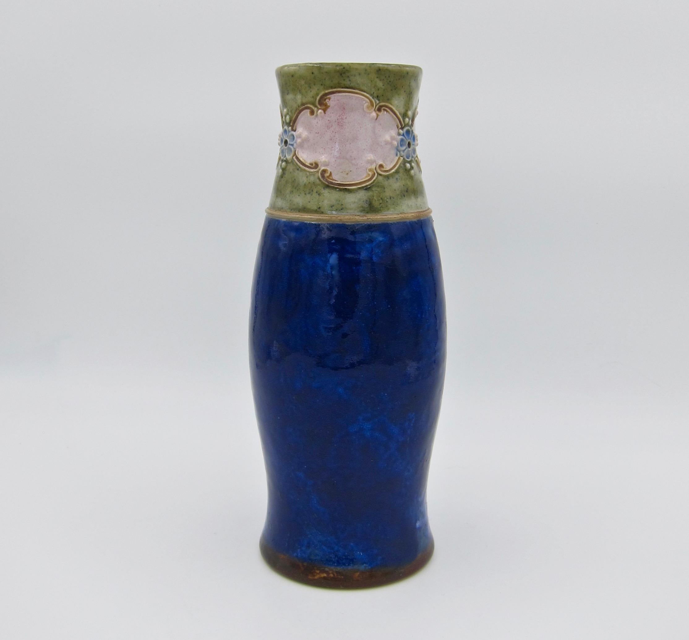 An early 20th century cylindrical stoneware vase from Royal Doulton of England, date marked for the period between 1902-1922. The vessel is hand-decorated in the Art Nouveau style; the upper part of the vase features relief moulded blue flowers