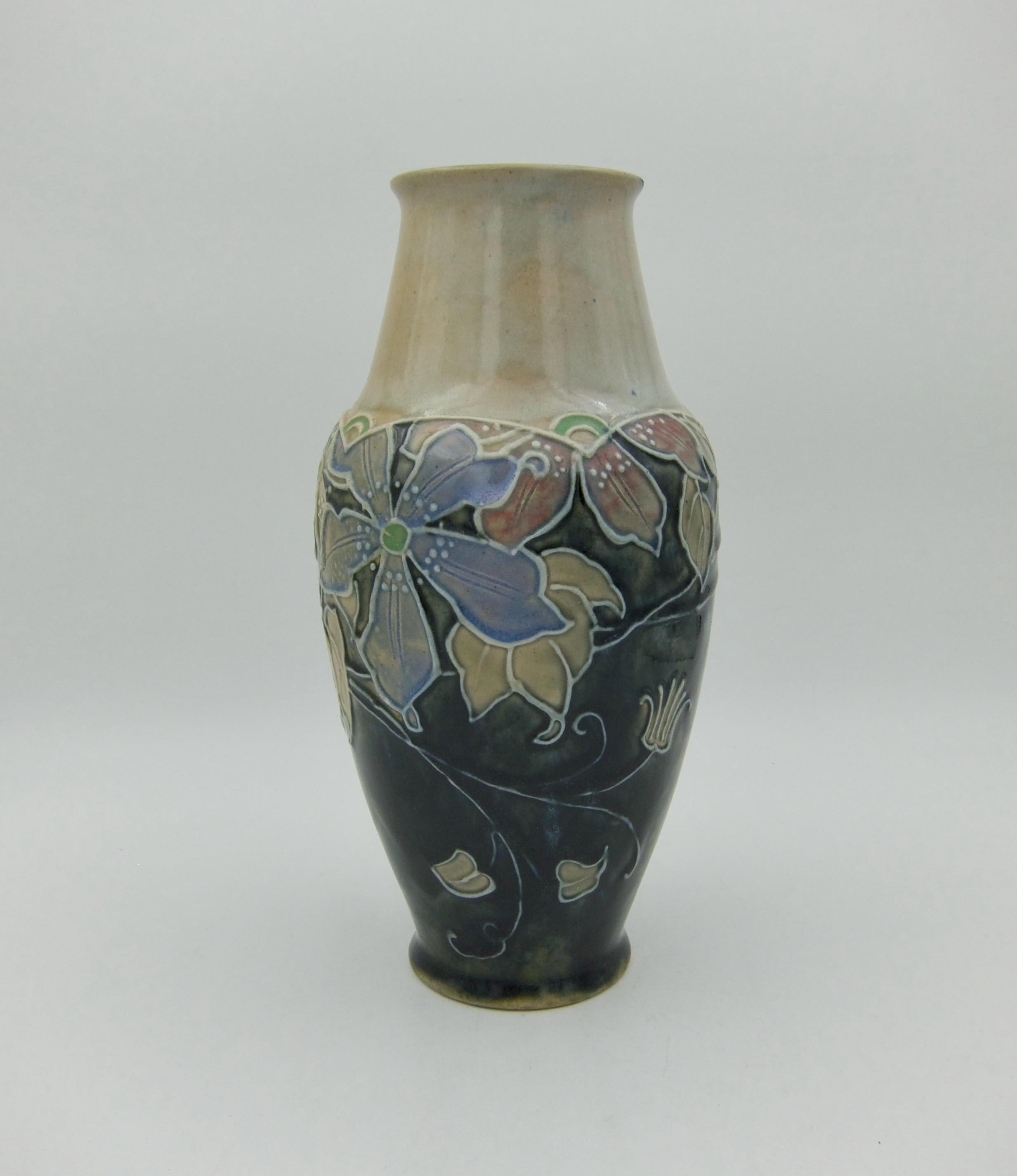 A hand-painted stoneware vase from Royal Doulton of England, dating circa 1920s. The art pottery vase was decorated by Joan Honey in the Art Nouveau style featuring stylized, tube lined flowers, leaves, and vines in shades of pale pink, blue, and