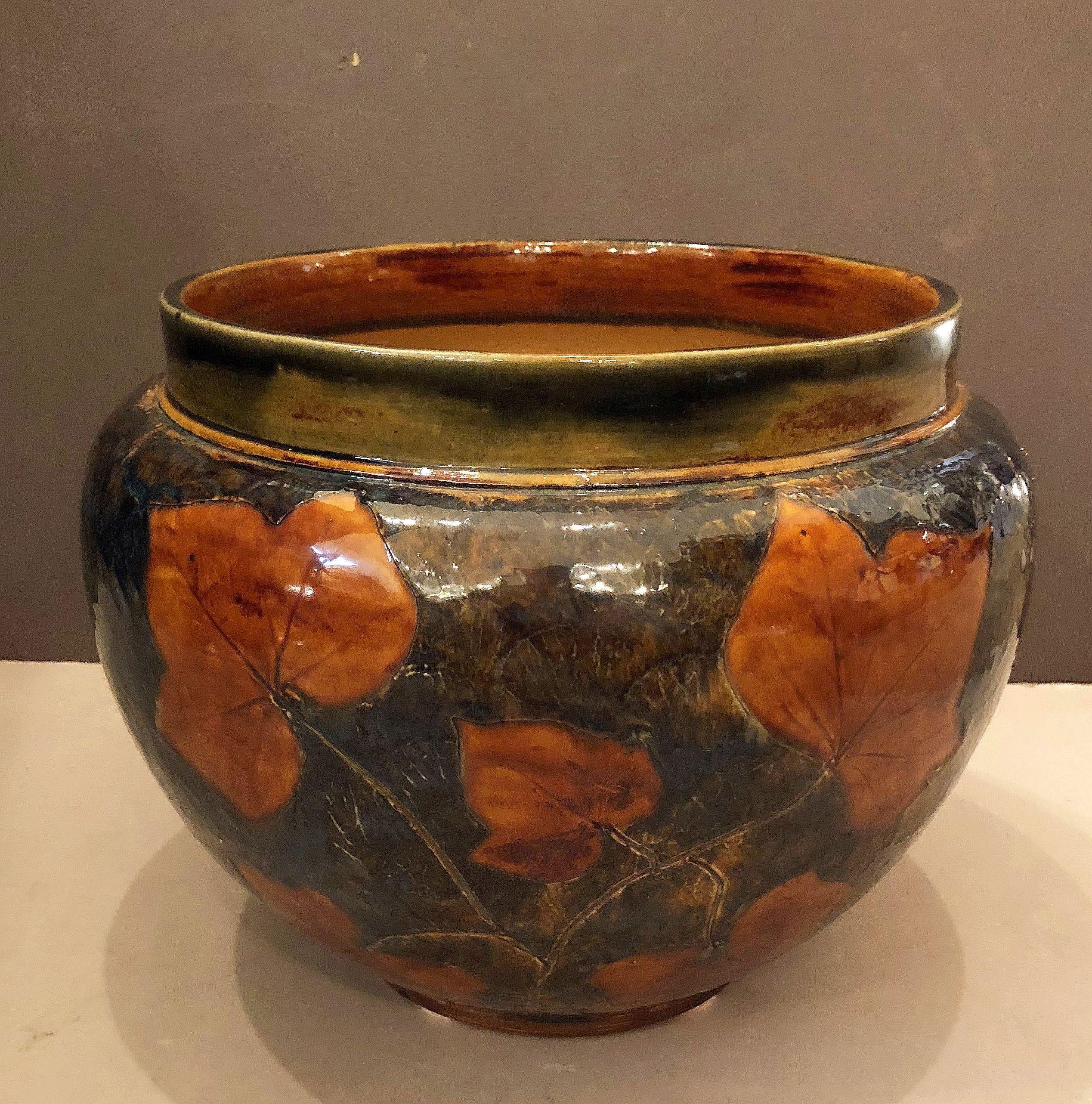A fine English jardiniere or garden pot planter of salt-glazed stoneware pottery, from the Arts & Crafts era, by the celebrated art pottery firm, Royal Doulton.

Pattern known as Autumn Leaves.

Impressed marks to base: Royal Doulton mark and