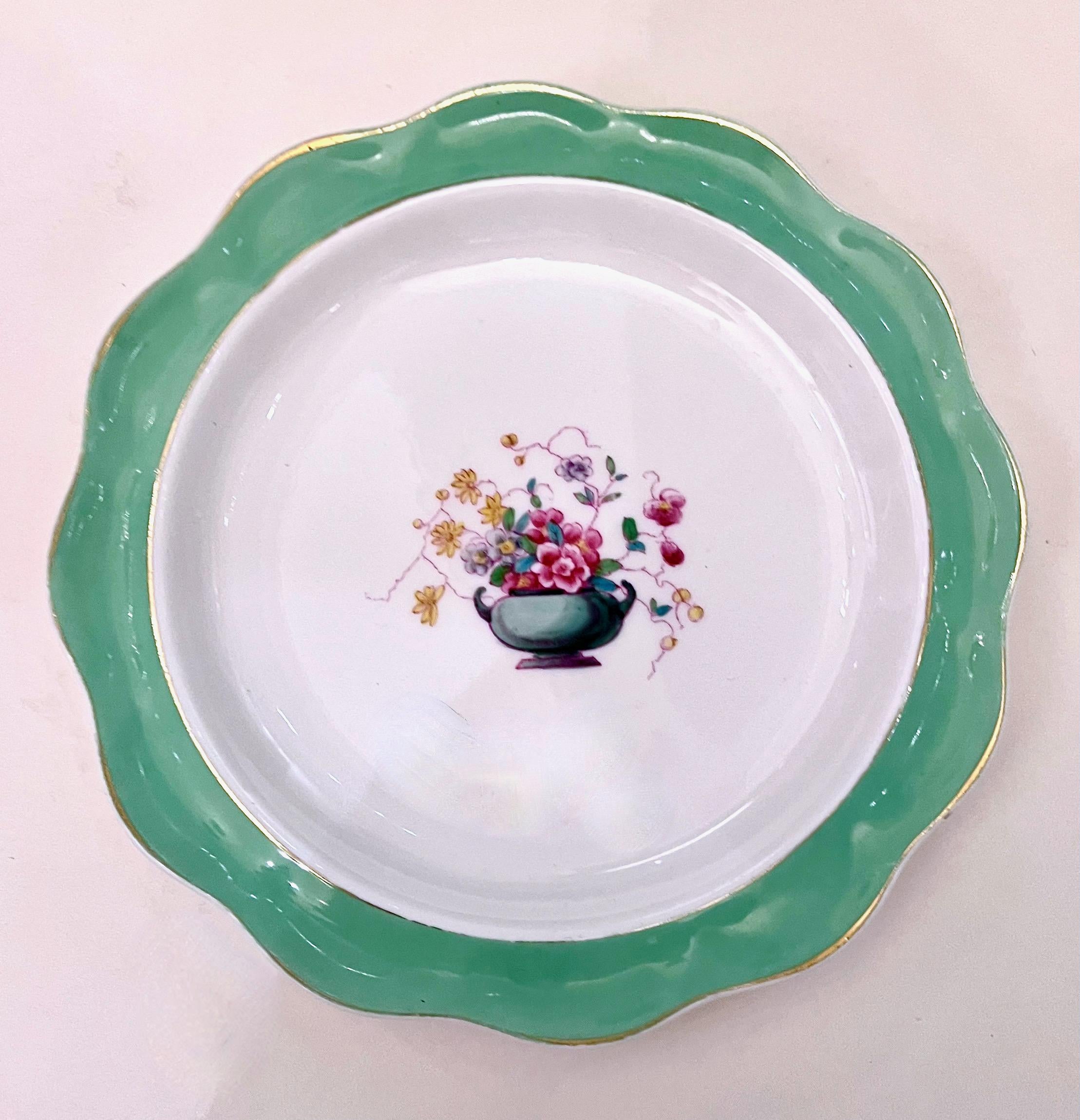 This is a charming set of 14 Royal Doulton hand painted luncheon plates that date to the early 20th century. The scolloped rims of the plates are decorated with a beautiful hand-painted band of subtle turquoise and a hand-painted floral spray in an