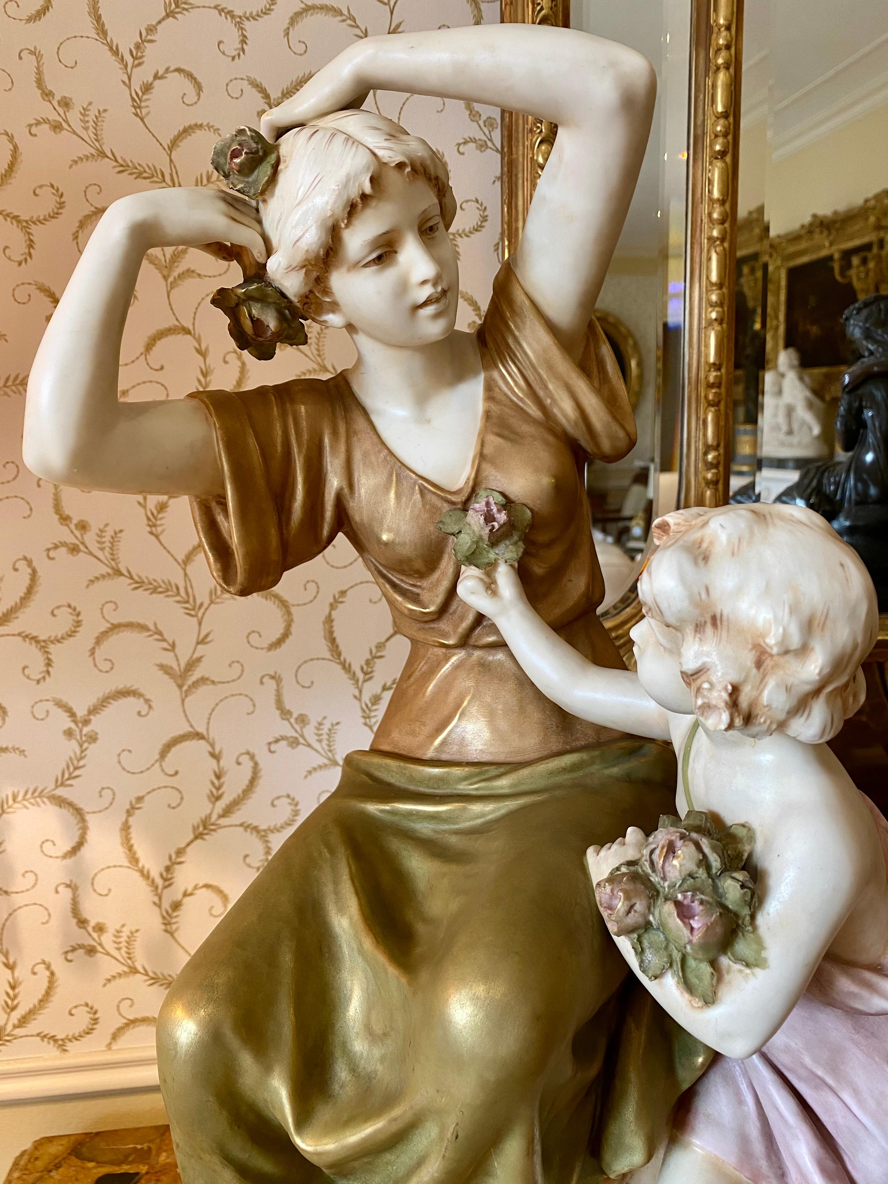 Polychrome porcelain group with gold highlights representing a young girl offering flowers to her mother to hang them in her hair. Signed with the Royal Dux stamp below and marked on the back with the initials 