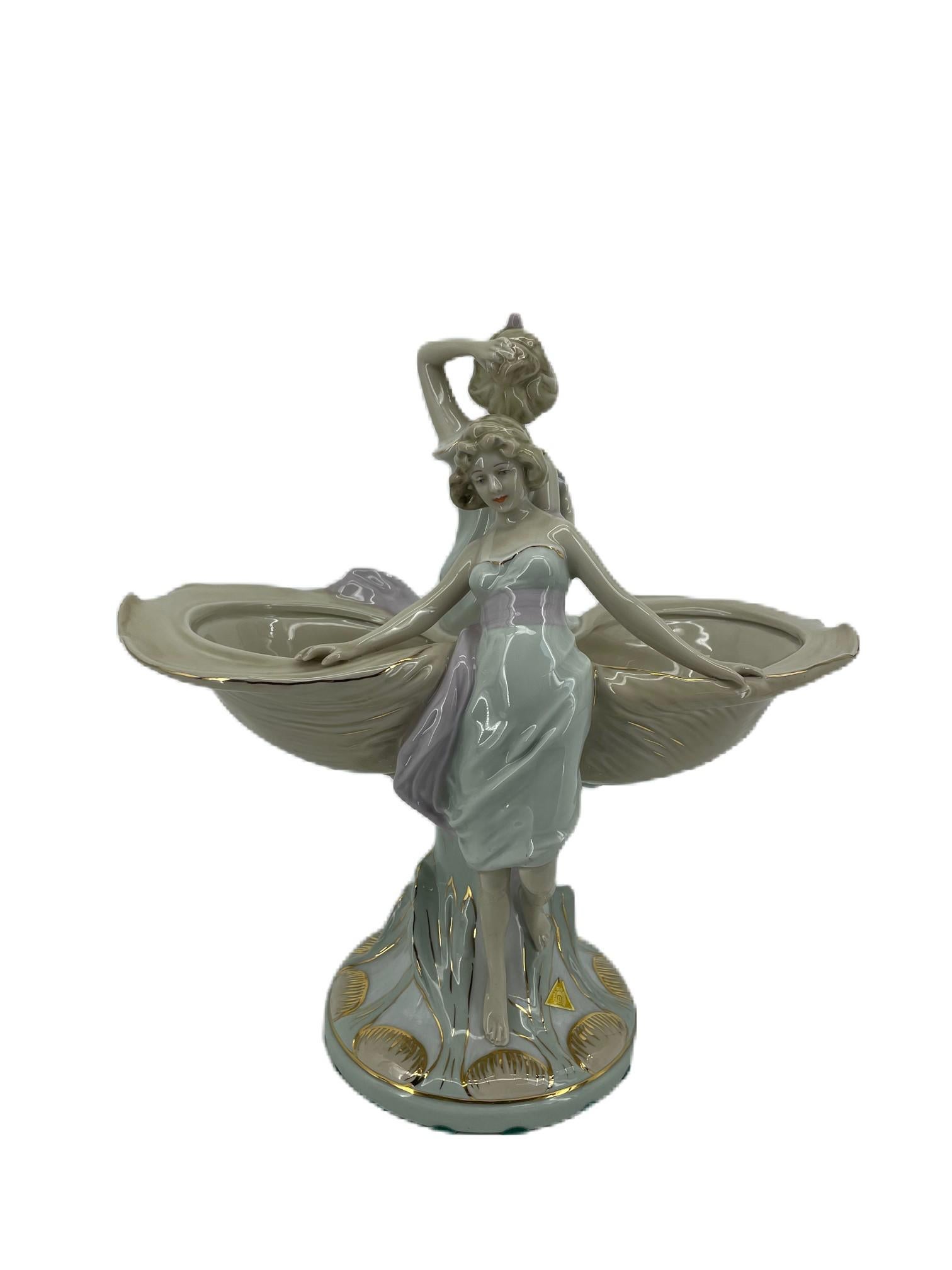 Figurine Royal Dux
Impressionnante figurine en porcelaine peinte à la main, représentant deux plats en forme de coquille surmontés de deux jeunes filles, reposant sur une base rustique étalée, dans des couleurs pastel brillantes à dominante crème,