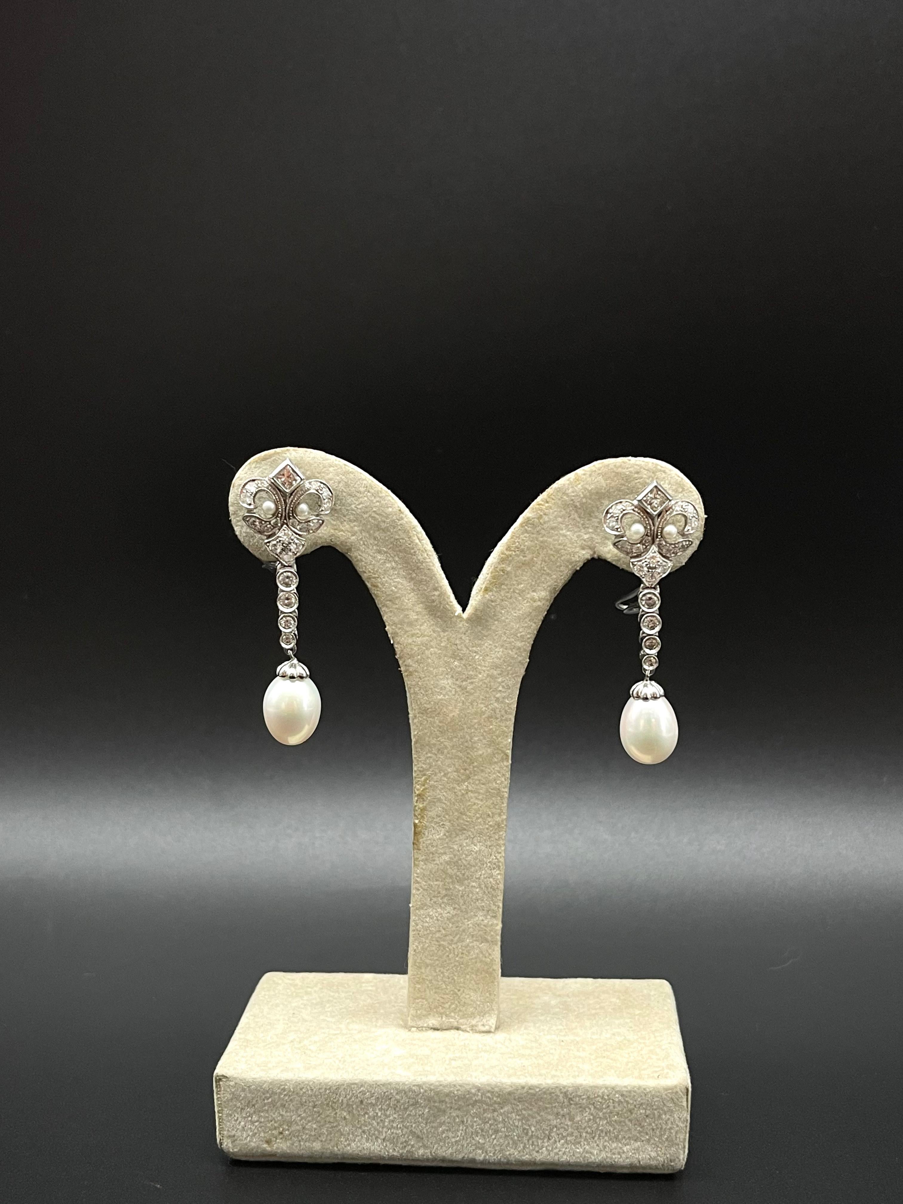 A breathtaking pair of Portuguese White Gold and diamond and seed pearl earrings in the shape of a Royal Fleur-de-Lis with two Pearls as pendants.

Graceful in design, these stunning pearl earrings are crafted in 19.2 Karat Portuguese white gold and